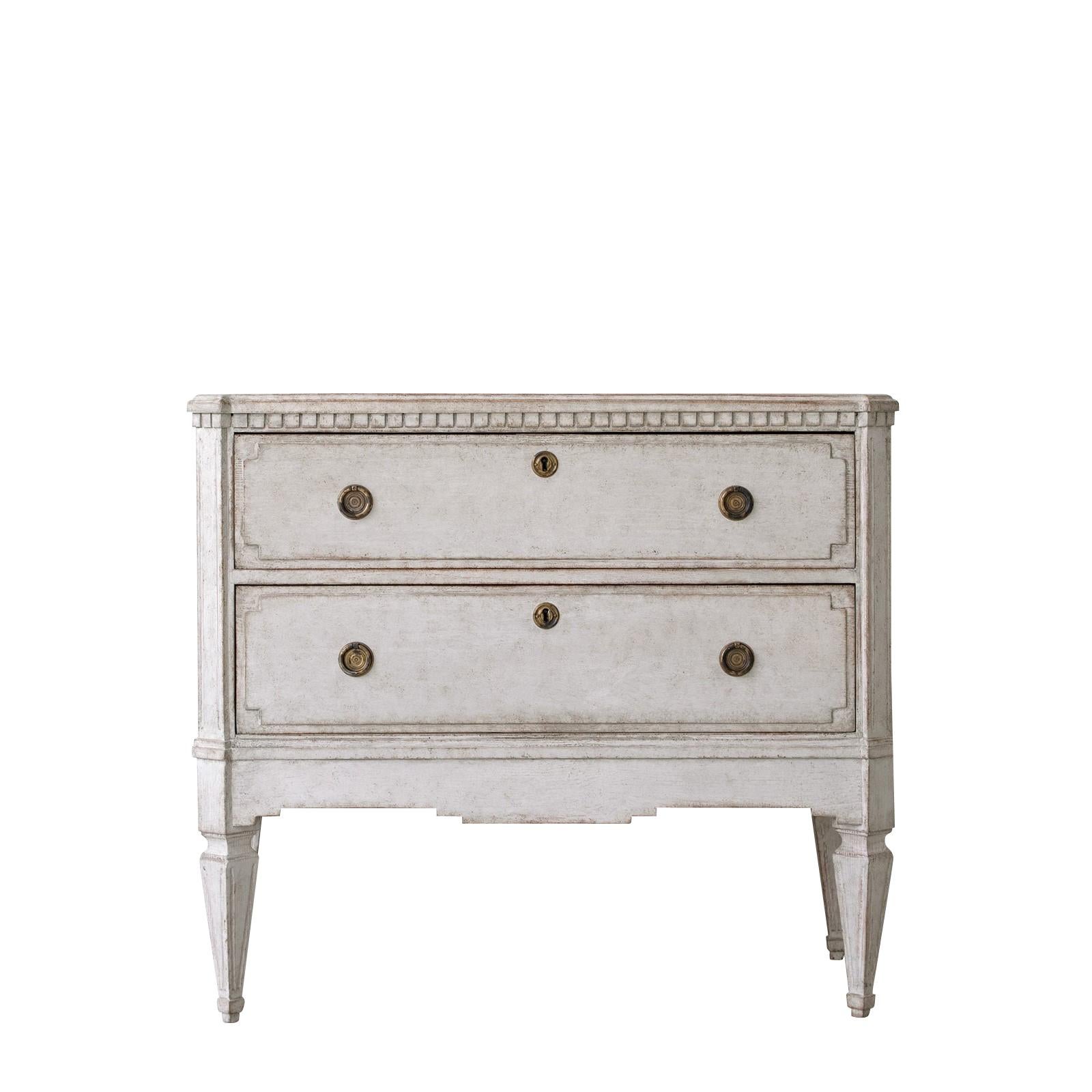 19th century Swedish pair of Gustavian style commodes.
Soft grey patina.
Dental frieze border, canted & fluted corners.
Two drawers with raised paneled fronts and geometric square cut-out corners.
Square tapered legs with scalloped tops & fluted