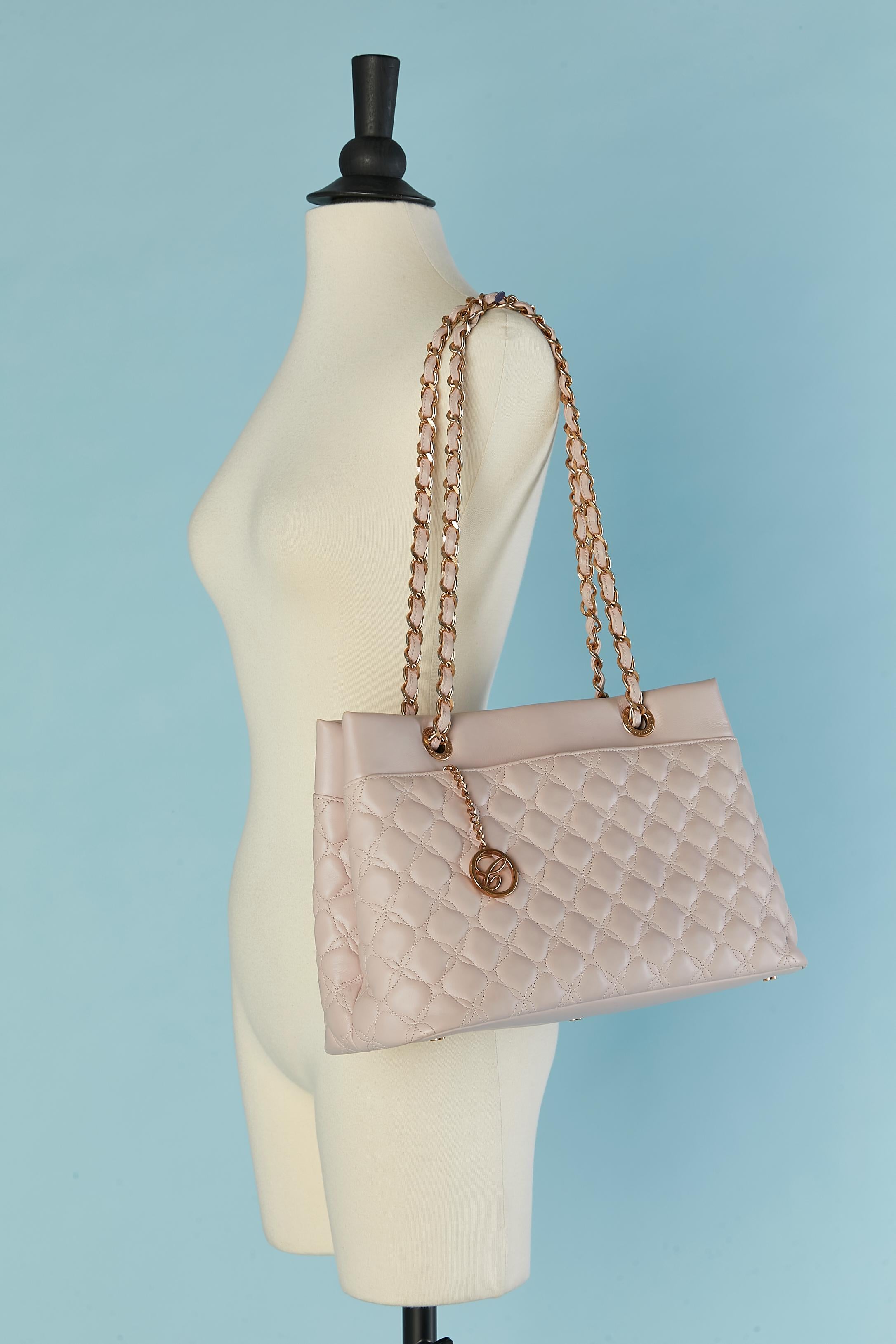 Pale pink top-stitched leather bag quilted and top handle in chain and leather. Branded nylon lining. 2 flat pockets on each side and 3 pockets inside the bag ( 1 with zip closure) Key ring holder attach to a gold metal chain. 
Snap on both side and