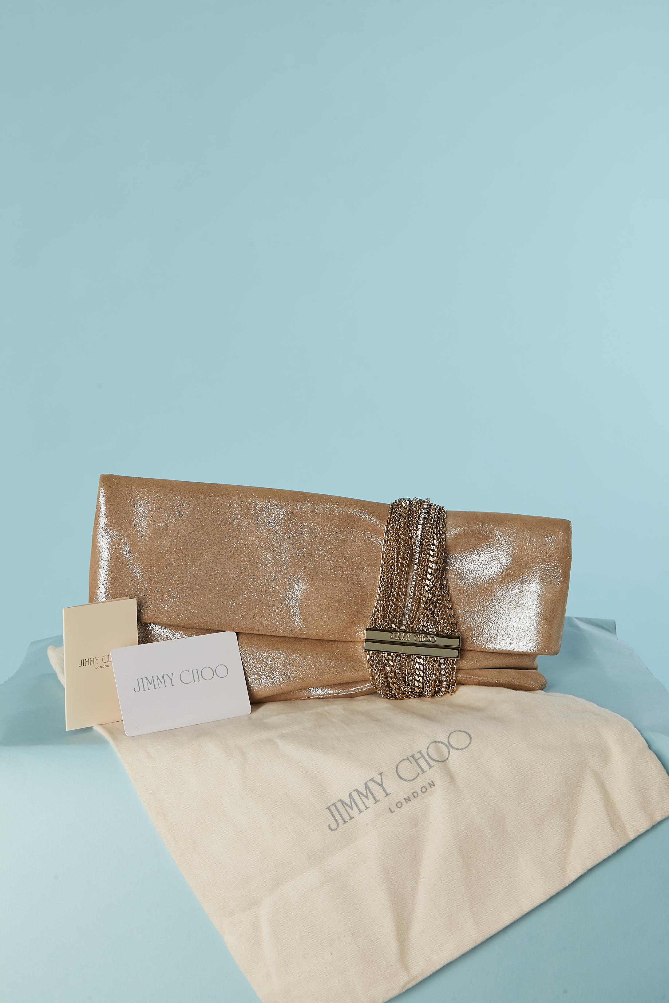 Pale shinny gold clutch with gold metal chain and rhinestone closure. Ivory satin lining inside with one zipped pocket. Magnet claps closure in gold metal hardware. Snap closure under the flap. 
Authenticity card provided + authenticity hologram
