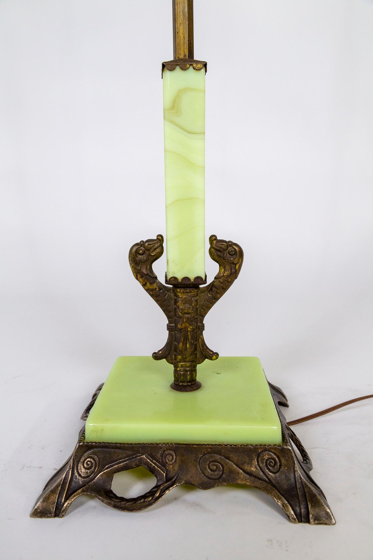 An early 20th century floor lamp with a reeded, brass stem with segments of uranium, yellow-green glass throughout; accented with a blown glass amber and white bead. It has a decoratively cast, solid base with organic and fauna details and topped