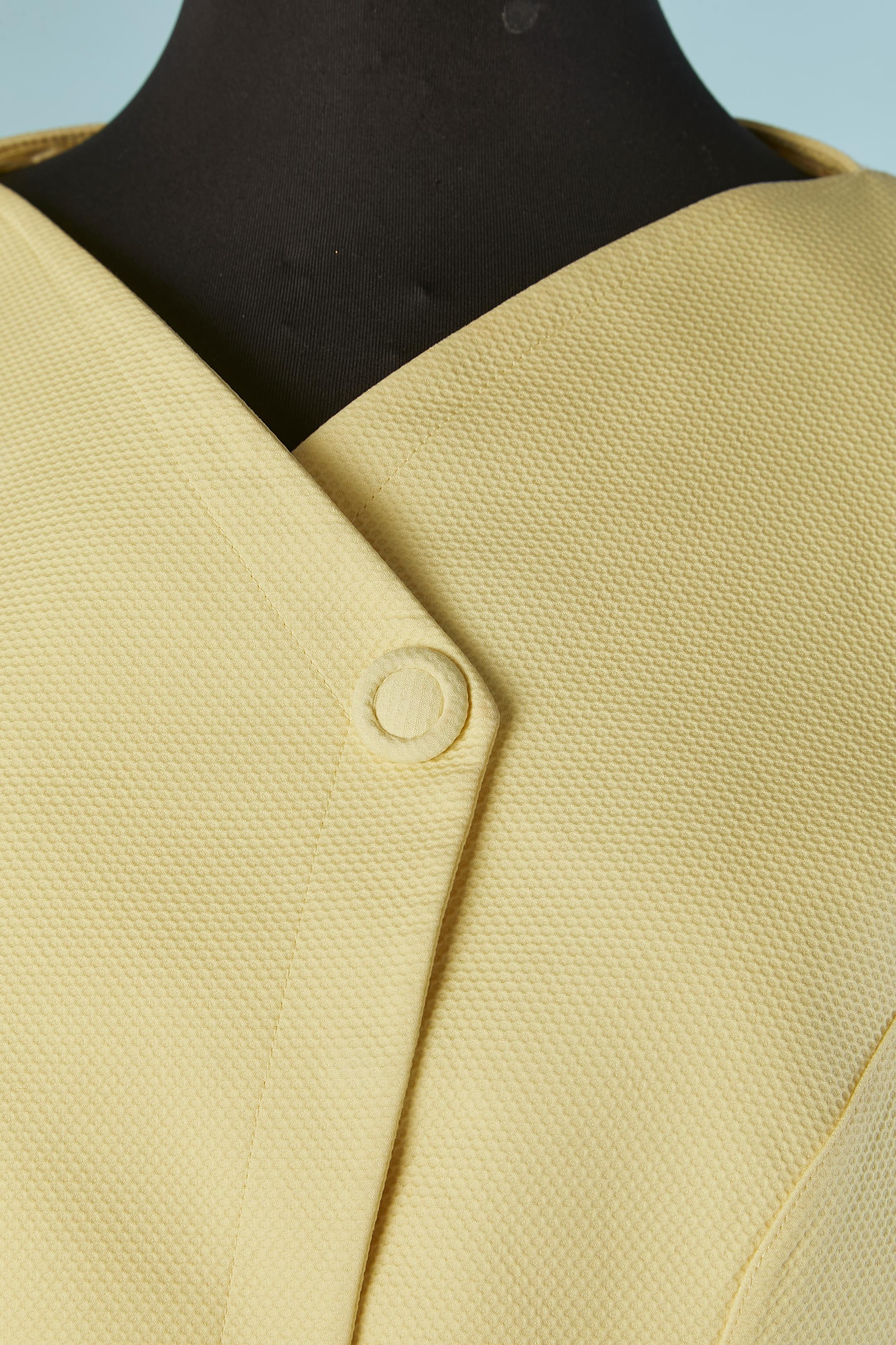 Combinaison jupe en piqué de coton jaune pâle. Doublure en acétate ou en rayonne. Fente sur les deux côtés de la veste. Mince pad d'épaule. Fermeture à pression cachée sur le milieu du devant. 
TAILLE 42 (Fr) L 