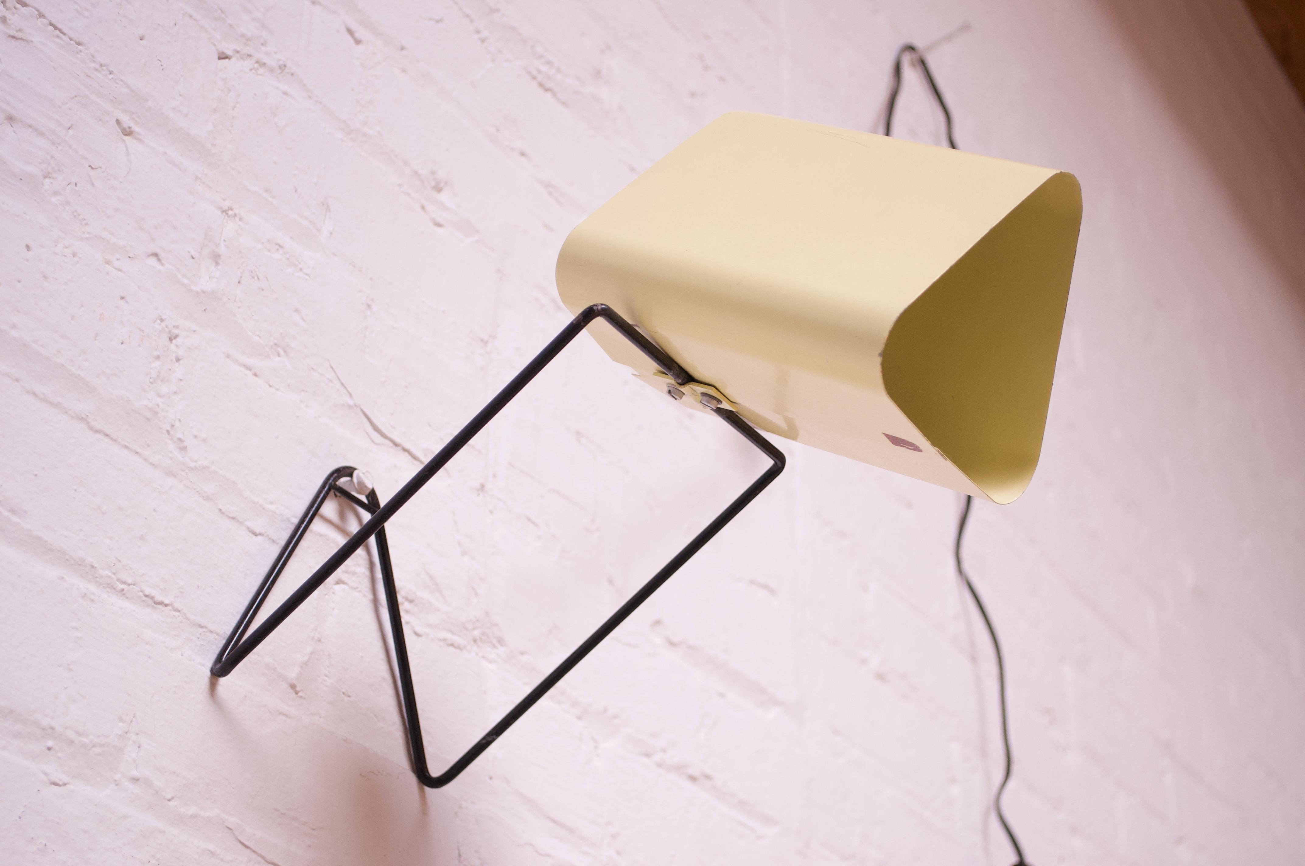 Versatile adjustable Dutch reading / table lamp or wall sconce by Philips (ca. 1950s, Netherlands).
Composed of a soft yellow triangular shade mounted to a painted black metal base with a slot for optional wall mounting. 
Shade is adjustable