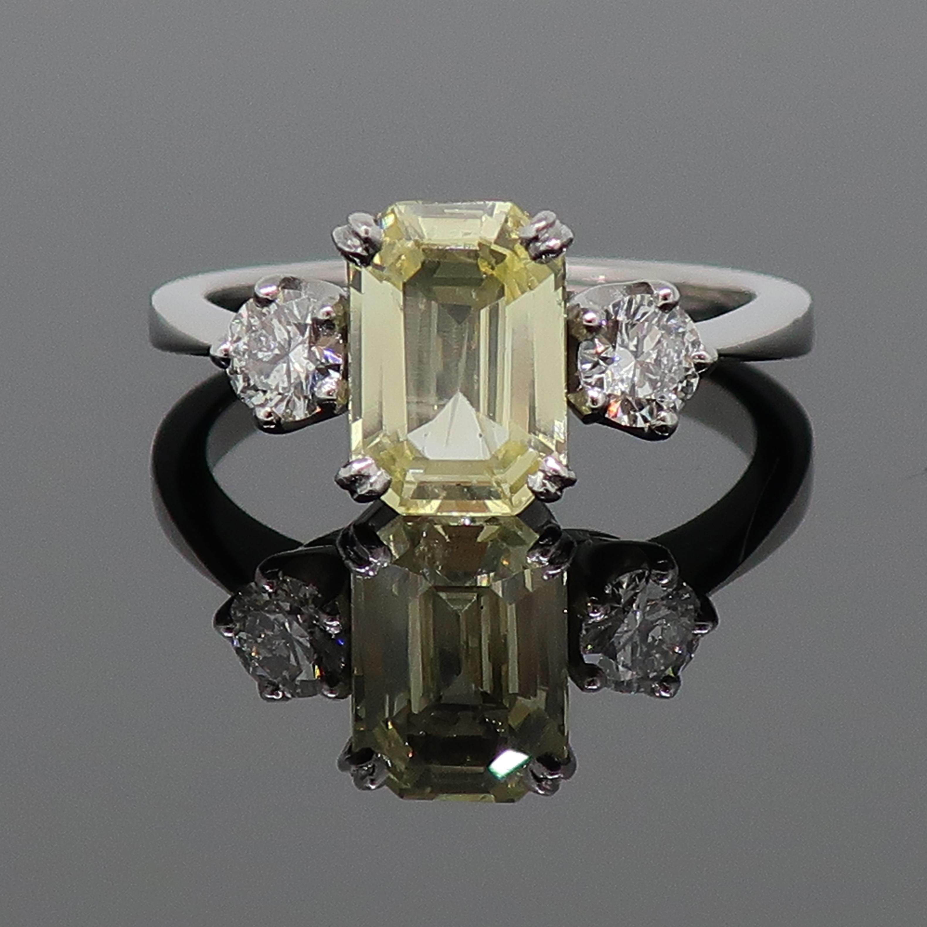 Yellow Sapphire and Diamond Three-Stone Ring 18 Karat White Gold

An emerald cut yellow sapphire & diamond three stone ring. Pale central yellow sapphire measuring 9.5mm x 6.6mm, set in four double claws, with a brilliant cut diamond either side set