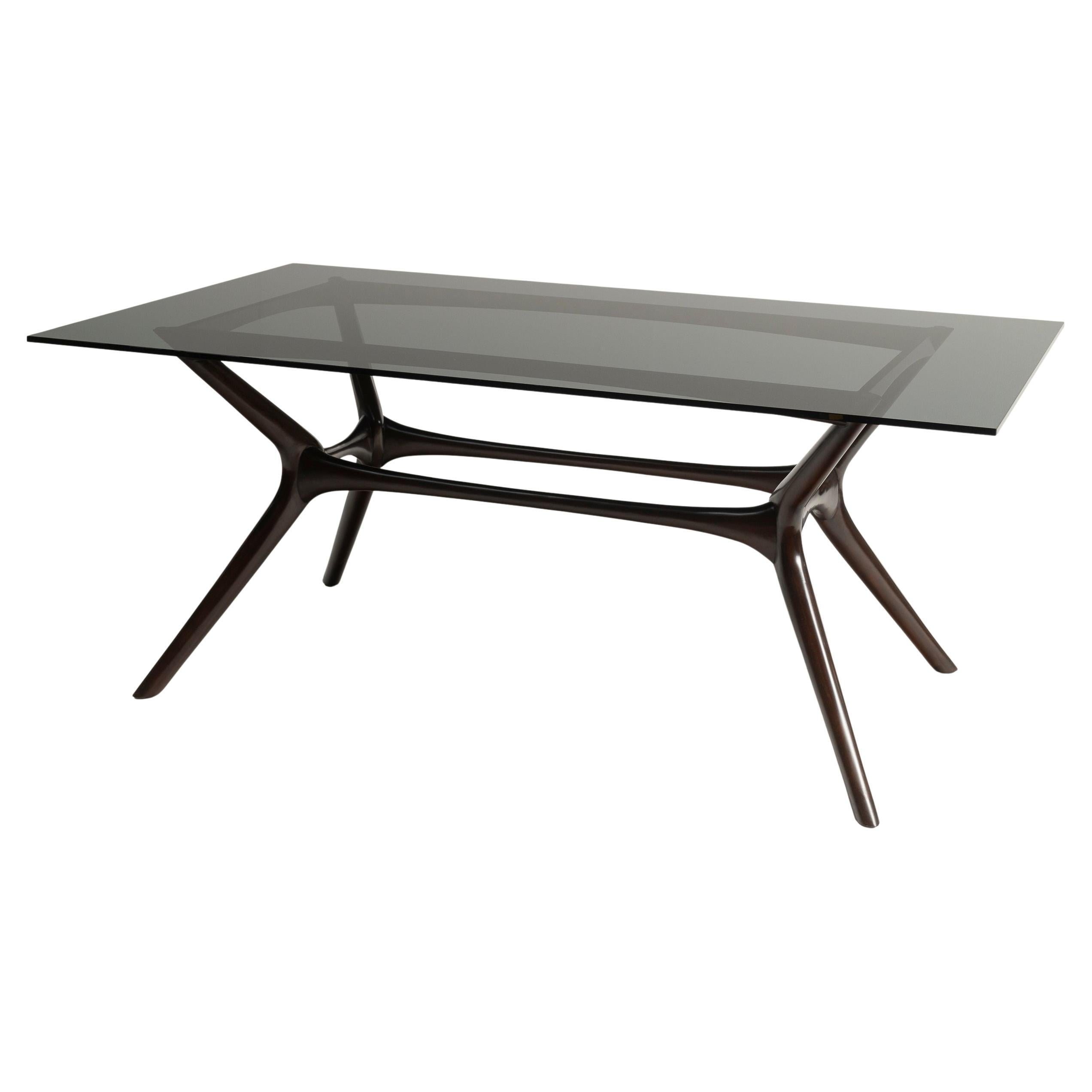 El estilo Mid Century Modern está presente en las líneas y la elegante silueta de esta preciosa mesa de comedor. Con una tapa de cristal ahumado y un elegante marco de caoba, esta pieza encaja a la perfección en muchos ambientes. Diseñado y