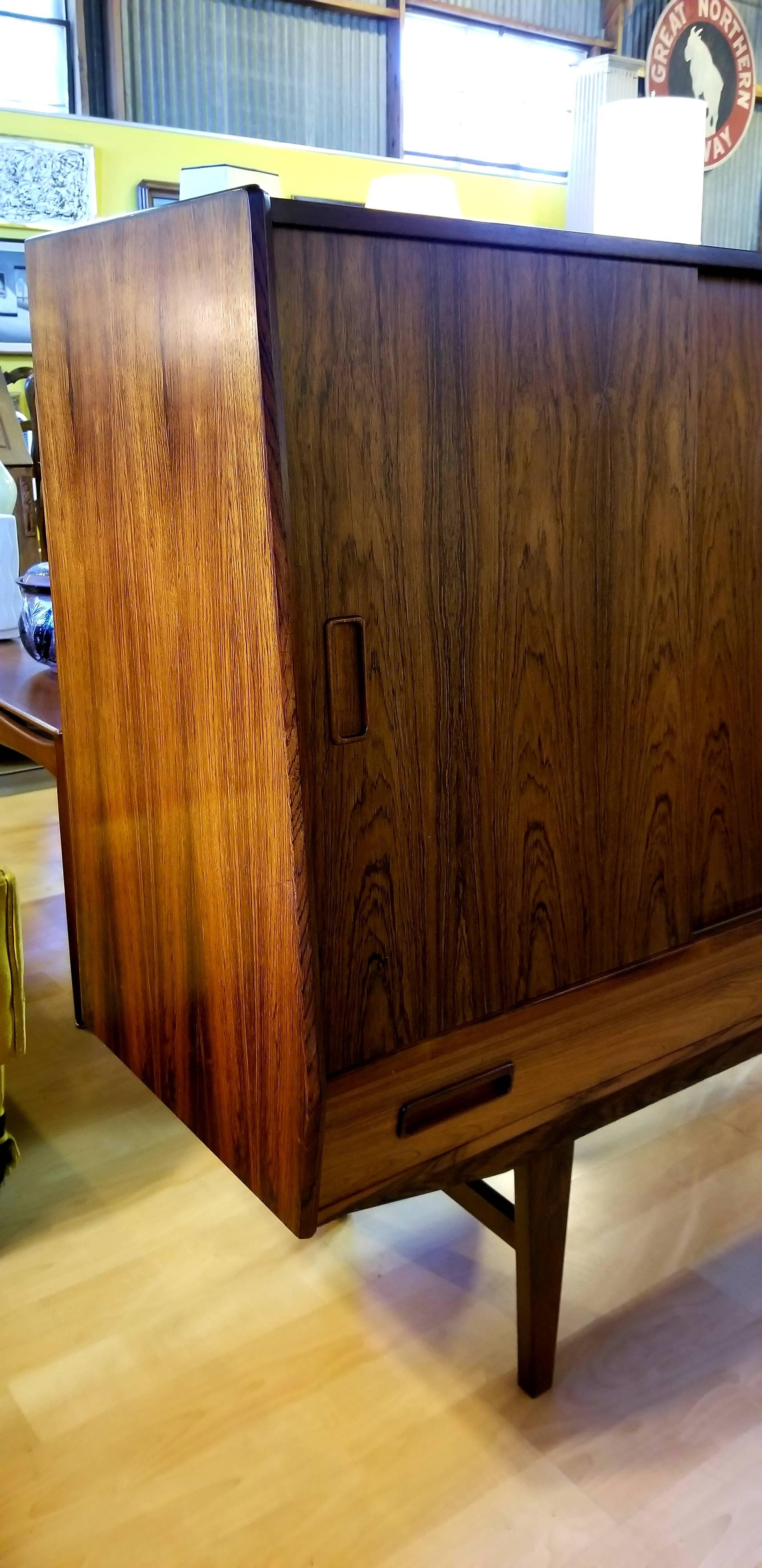 Beautiful, warm glow and figured wood grain to book matched rosewood credenza designed by Borge Seindal for Westergaards Mobelfabrik, Denmark, circa 1960s. Sliding doors with ample storage and center dry bar with mirrored back. Two lower drawers for