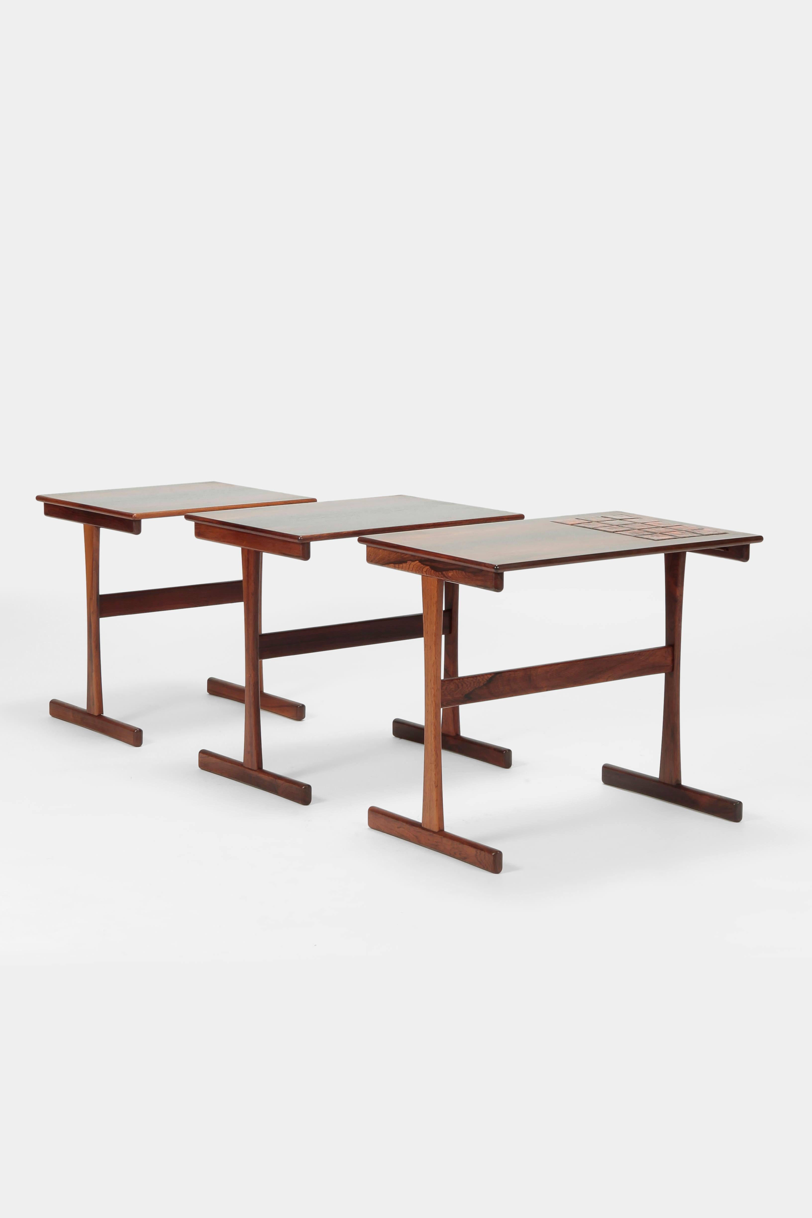 Three beautiful rosewood set tables designed by Kai Kristiansen with ceramic elements on the largest table, manufactured by Vildbjerg Mobelfabrik in the 1960s. Beautiful warm wooden structure, very sculpturally created objects, practically sliding