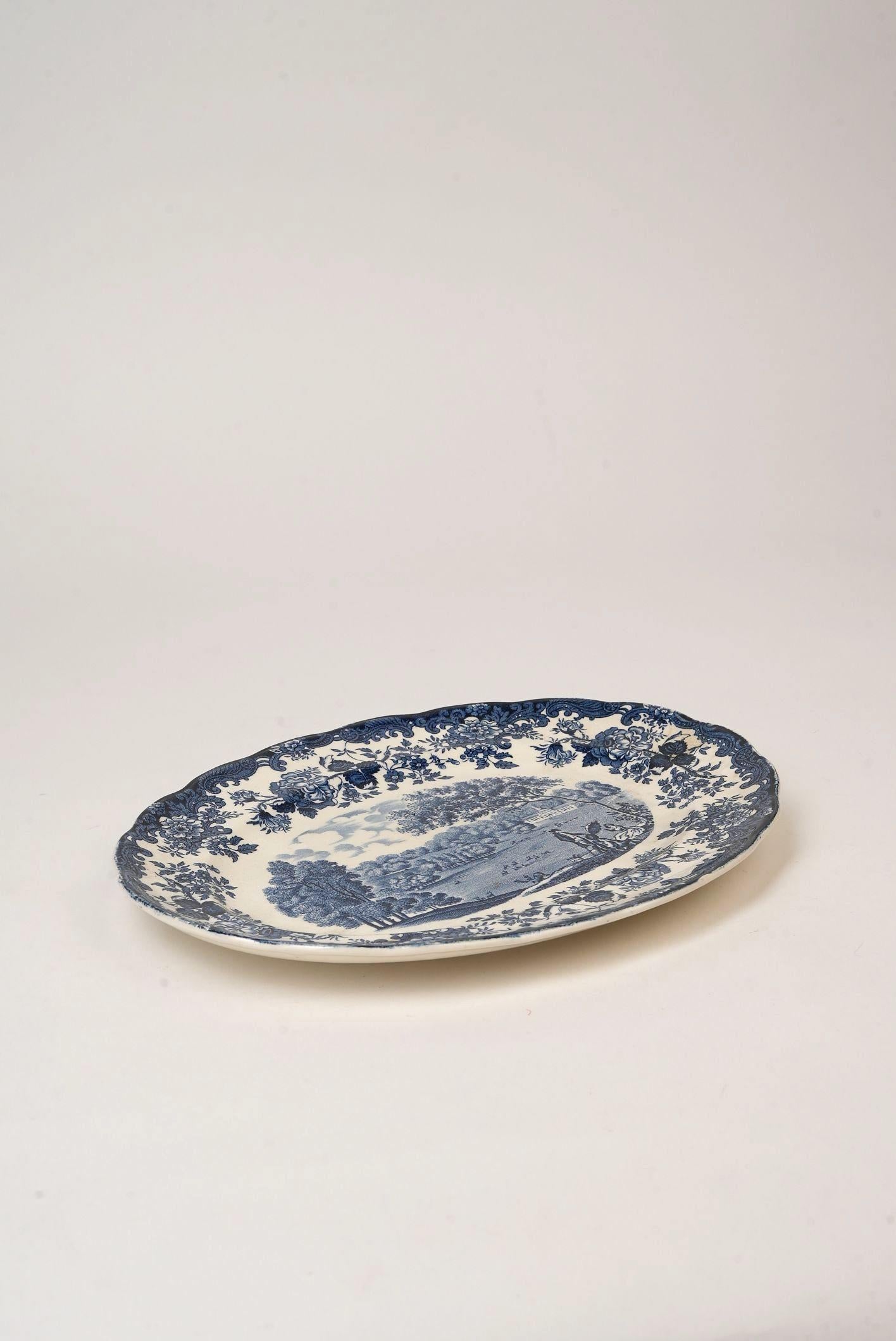 Ce magnifique plat en transferware bleu et blanc de Palissy, une poterie historique du Staffordshire et plus tard filiale de Royal Worcester, est une charmante incarnation de l'artisanat anglais et de la vie à la campagne. La pièce présente le motif