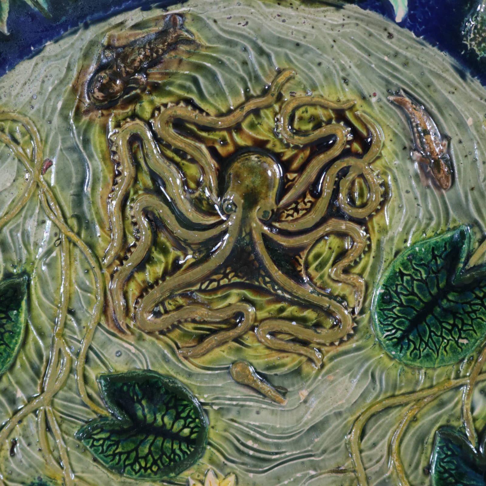 Assiette non identifiée en majolique française de Palissy représentant une pieuvre, des tortues, des poissons, des grenouilles, des lézards, des serpents, des poissons et des lys. Coloration : le bleu, le vert et le gris sont prédominants. Porte une