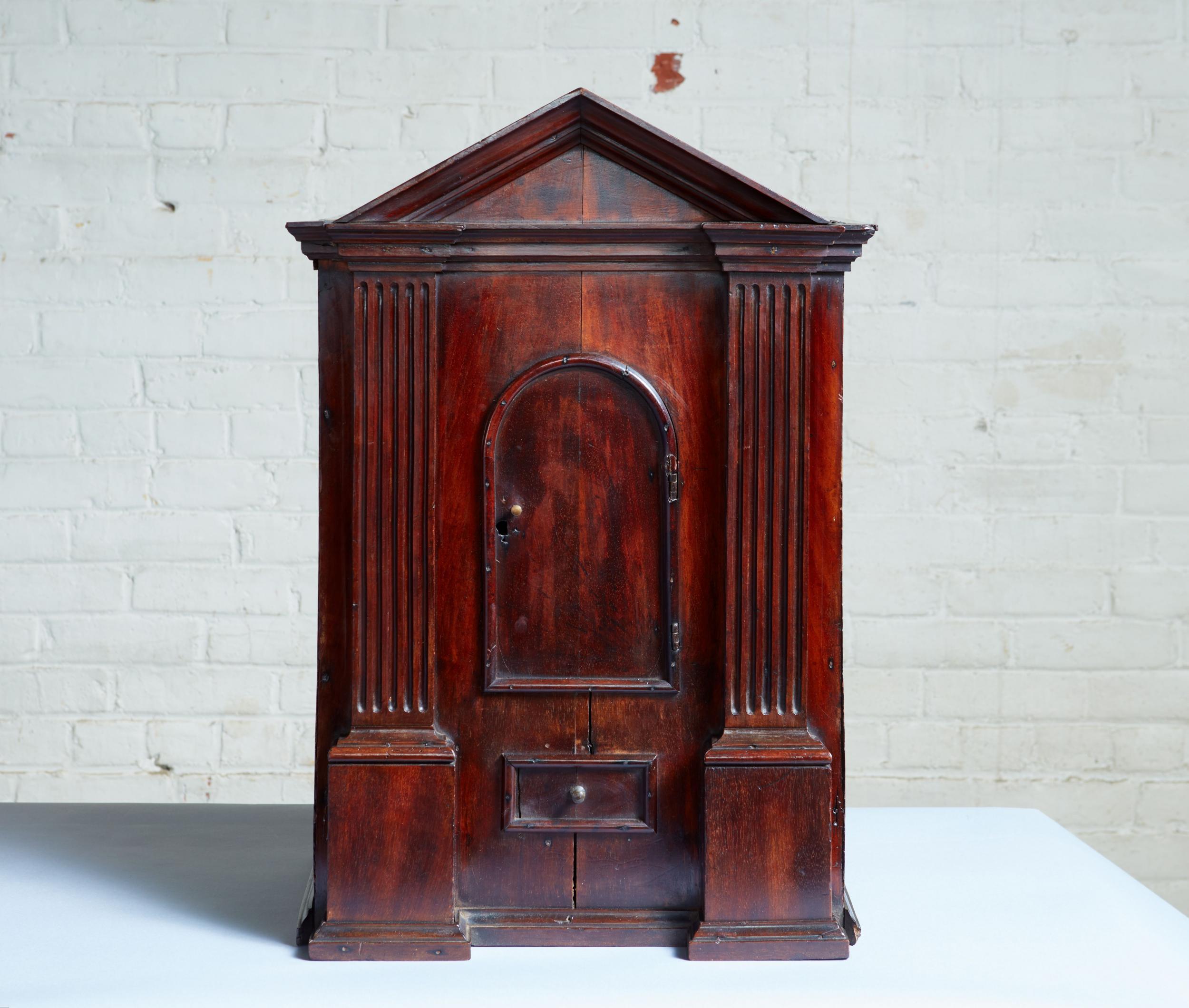Rare early 18th century walnut Palladian diminutive cabinet of architectural form having a pedimented top over pair of pilasters flanking a single arched door and having a molded base, the whole retaining a lovely old finish and great patina.