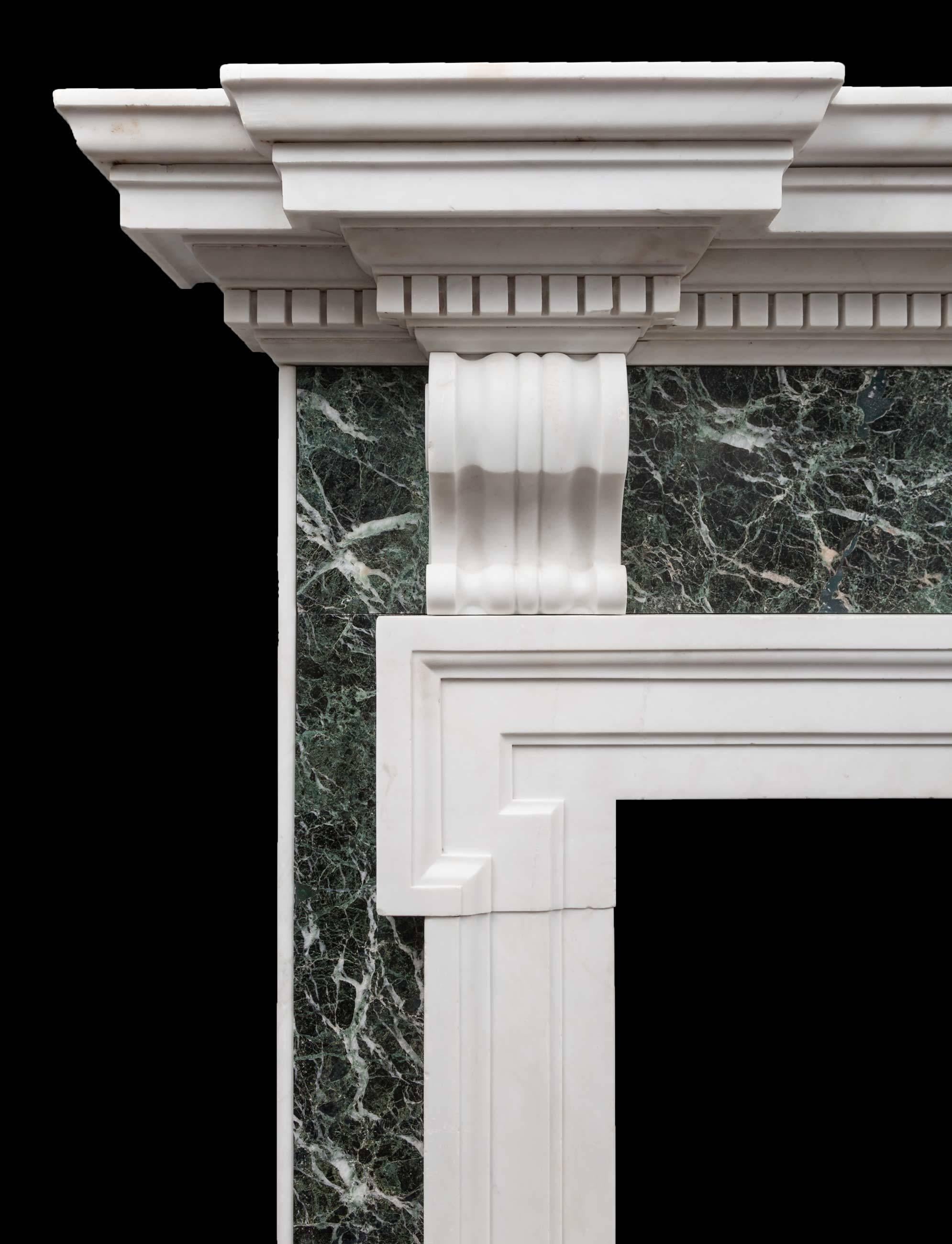 An antique green Verde Antico and white statuary Carrara marble fireplace in the Palladian style. Large in scale and wonderfully proportioned. The substantial dentil cornice rests on a Verde Antico frieze with two scrolled bracket corbels. The