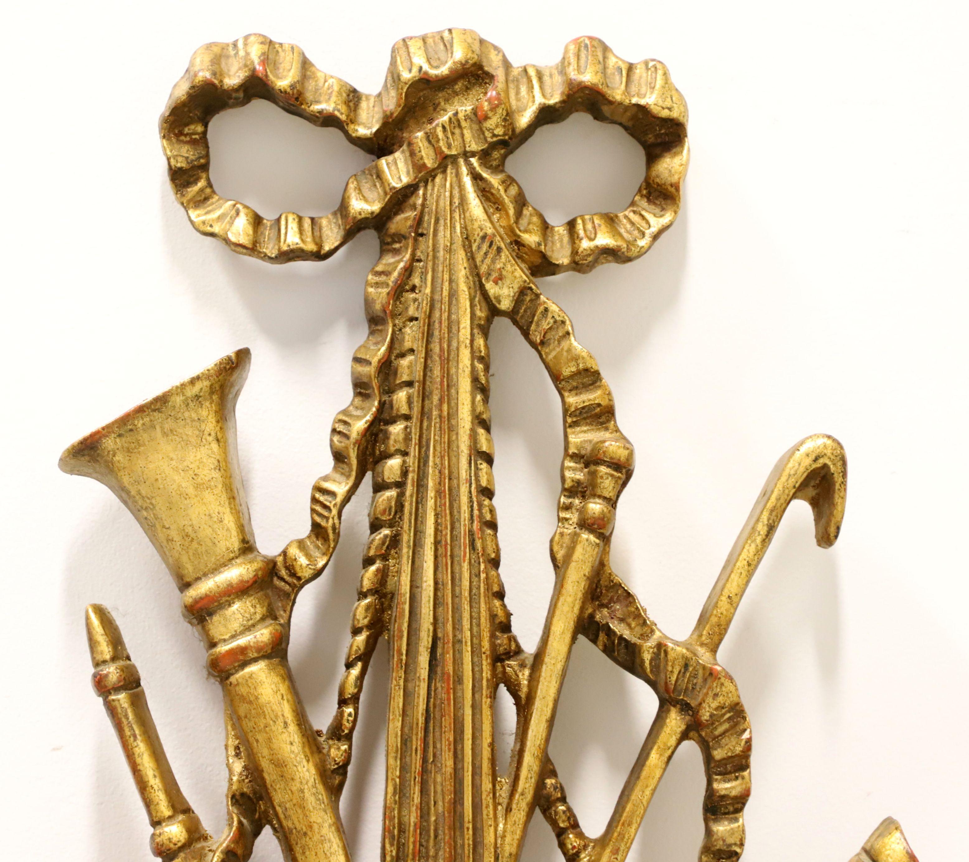 A pair Renaissance style of wood wall sculptures by Palladio. Solid wood carved in the shape of multiple musical instruments and painted gilt gold. Each has a hanger for wall placement. Originally manufactured for sale as an individual piece, sold