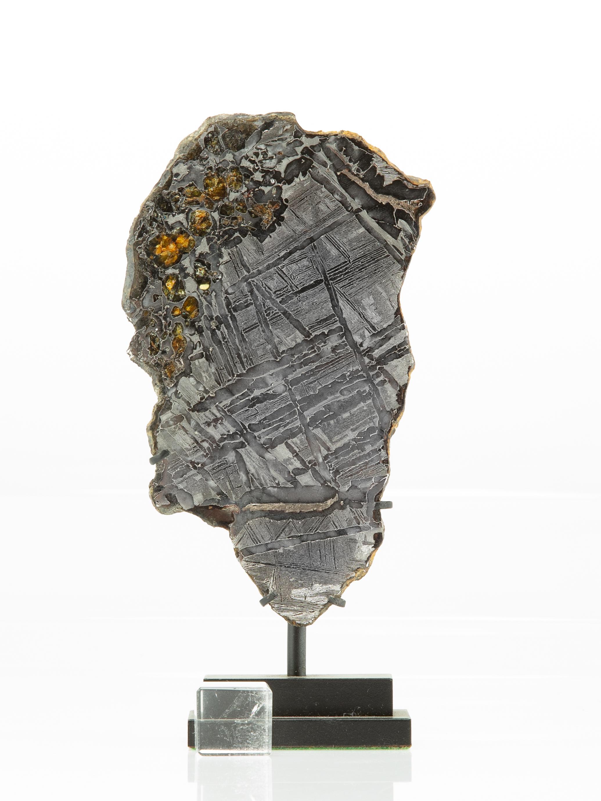 This is a complete slice of a meteorite pallasite with gemstones. Highly translucent olivine and peridot are plentiful and are fixed in a matrix, polished to mirror finish on one side and lightly etched on reverse to reveal crystalline structure of