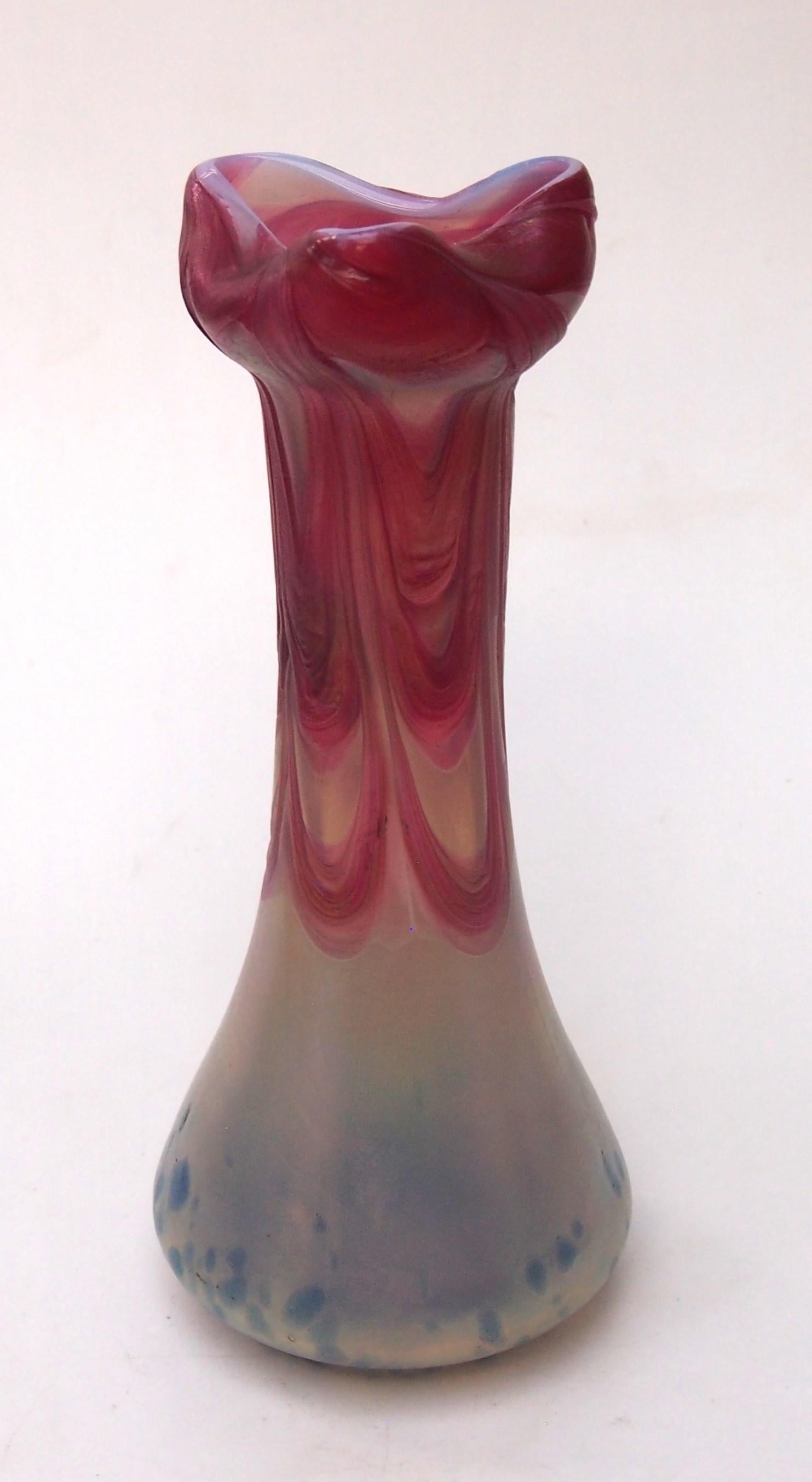 Un grand vase classique Pallme Koenig irisé à base ivoire avec d'épaisses guirlandes roses appliquées au sommet et des points bleus vibrants à la base, travaillé à la main, il a une base ronde, une taille qui se rétrécit et un sommet à trois côtés