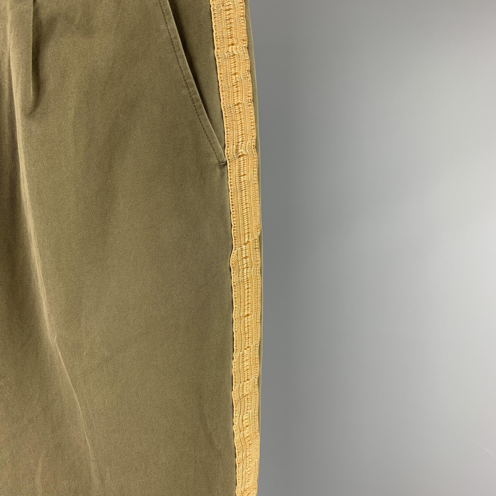PALM ANGELS dress pants comes in a olive cotton with a gold ribbon stripe design featuring a pleated style, regular fit, cuffed leg, and a button fly closure. Made in Italy.

Excellent Pre-Owned Condition.
Marked: IT 54
Original Retail Price: