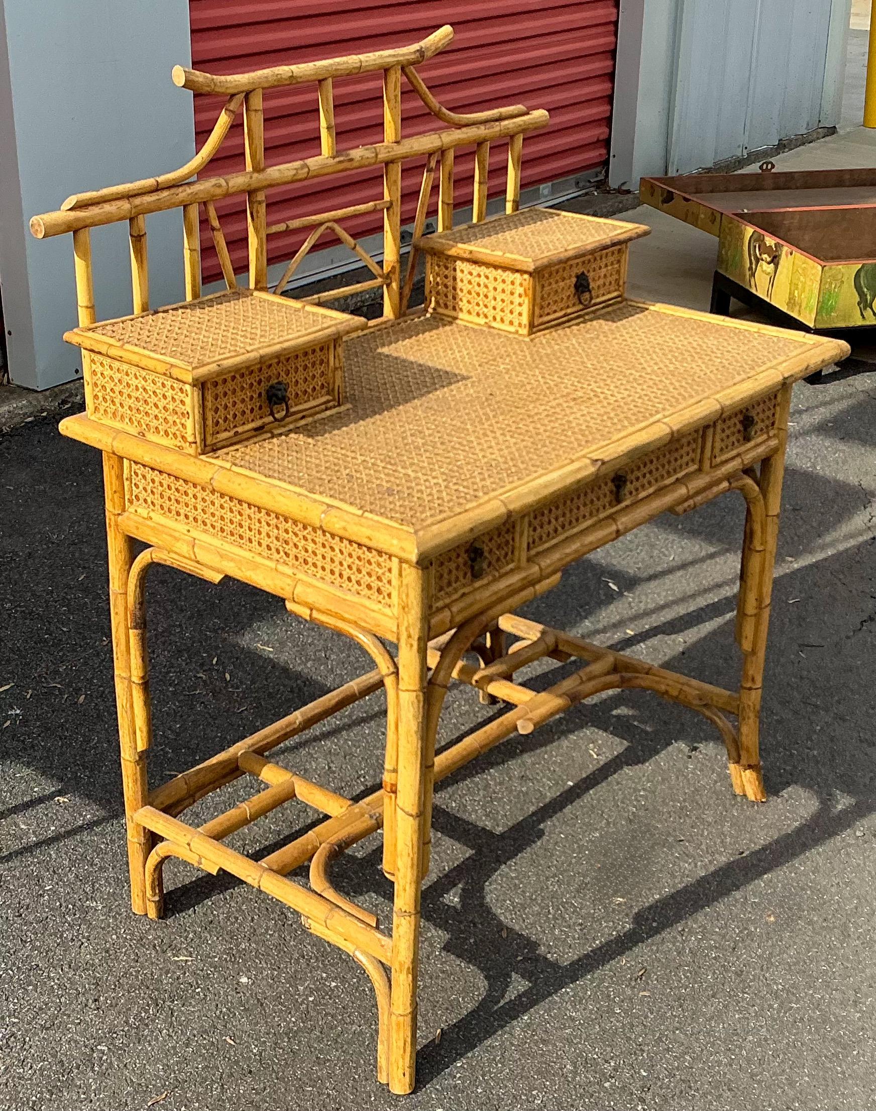 This is a Palm Beach chic bamboo and caned writing desk. It has a charming pagoda shape, and the drawers are dovetailed. It most likely dates to the 1970s. It is unmarked.