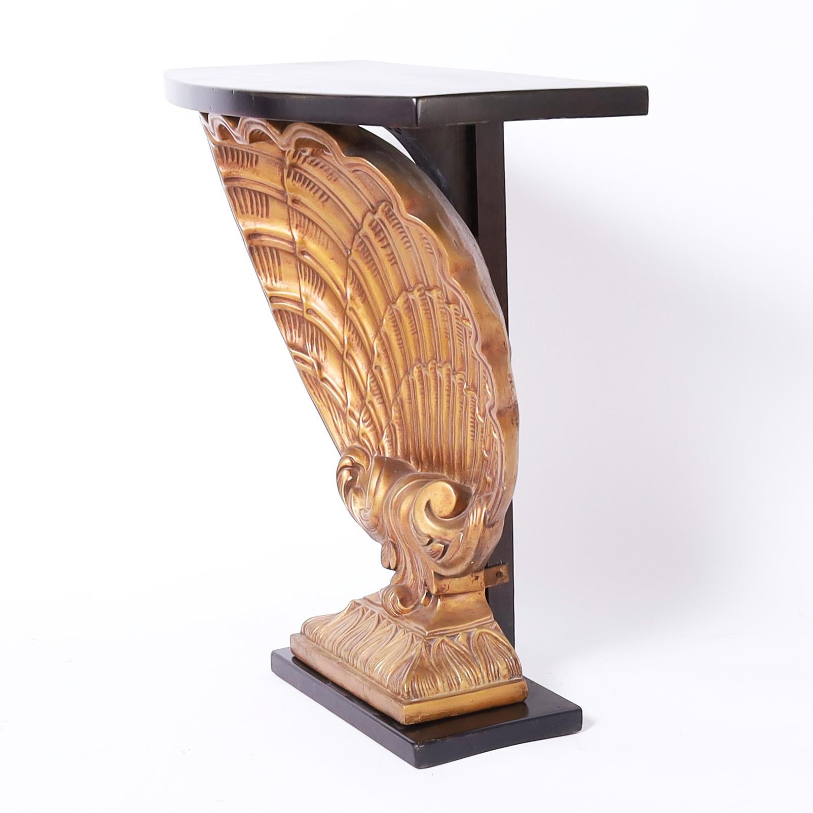 Vintage Hollywood style console table with a bow front top having a dark lush mahogany finish over a stylized plaster seashell with a gilt finish and lacquer base.