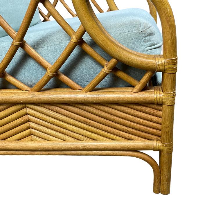 A beautiful coastal Palm Beach Regency-style rattan recliner with celadon upholstery. A fabulous way to bring the outdoors inside. Stacked bentwood rattan and bamboo arms flank each side of the chair, with geometric overlapping bamboo pieces under