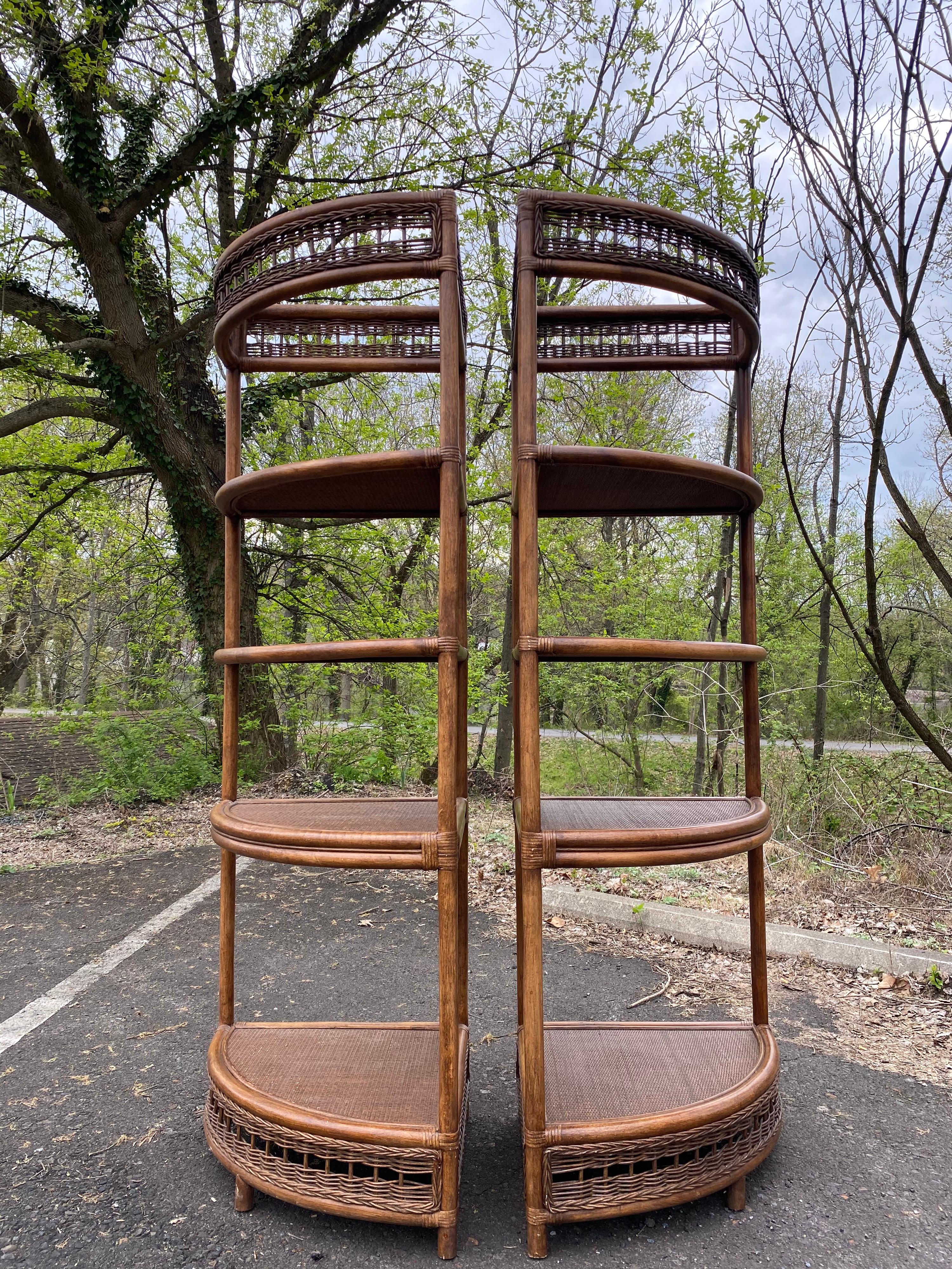 Pair of Mid-Century Modern bamboo rattan wicker étagère corner shelves. These tall sturdy Palm Regency style display bookcases feature curved fronts with decorative woven wicker banding at the top and bottom.