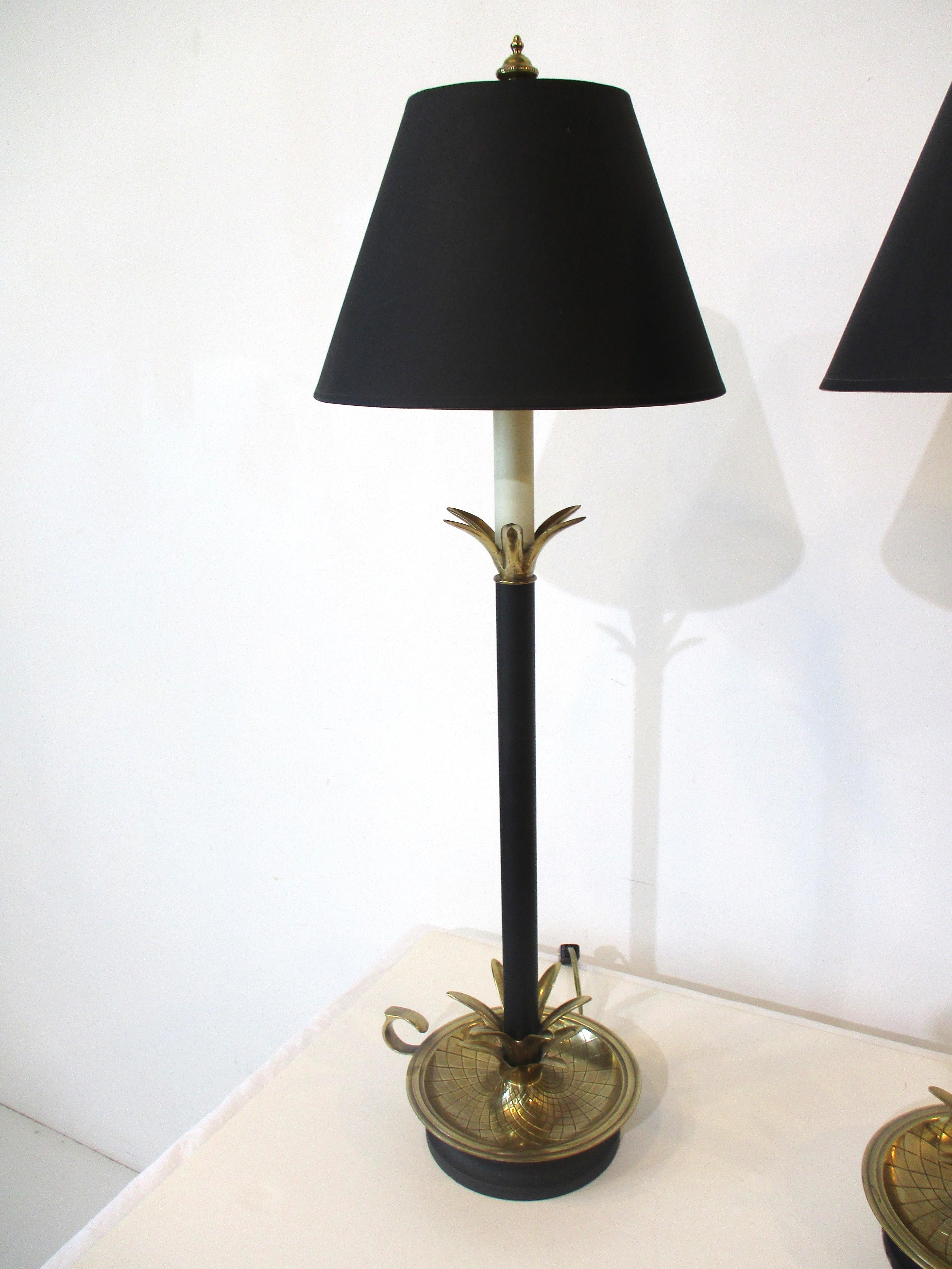 A pair of Regency styled Palm tree table lamps with satin black shades having gold toning to the inside . The solid brass leaves and base with details etched to the surface and the candlestick style make for a very well crafted and tight elegant