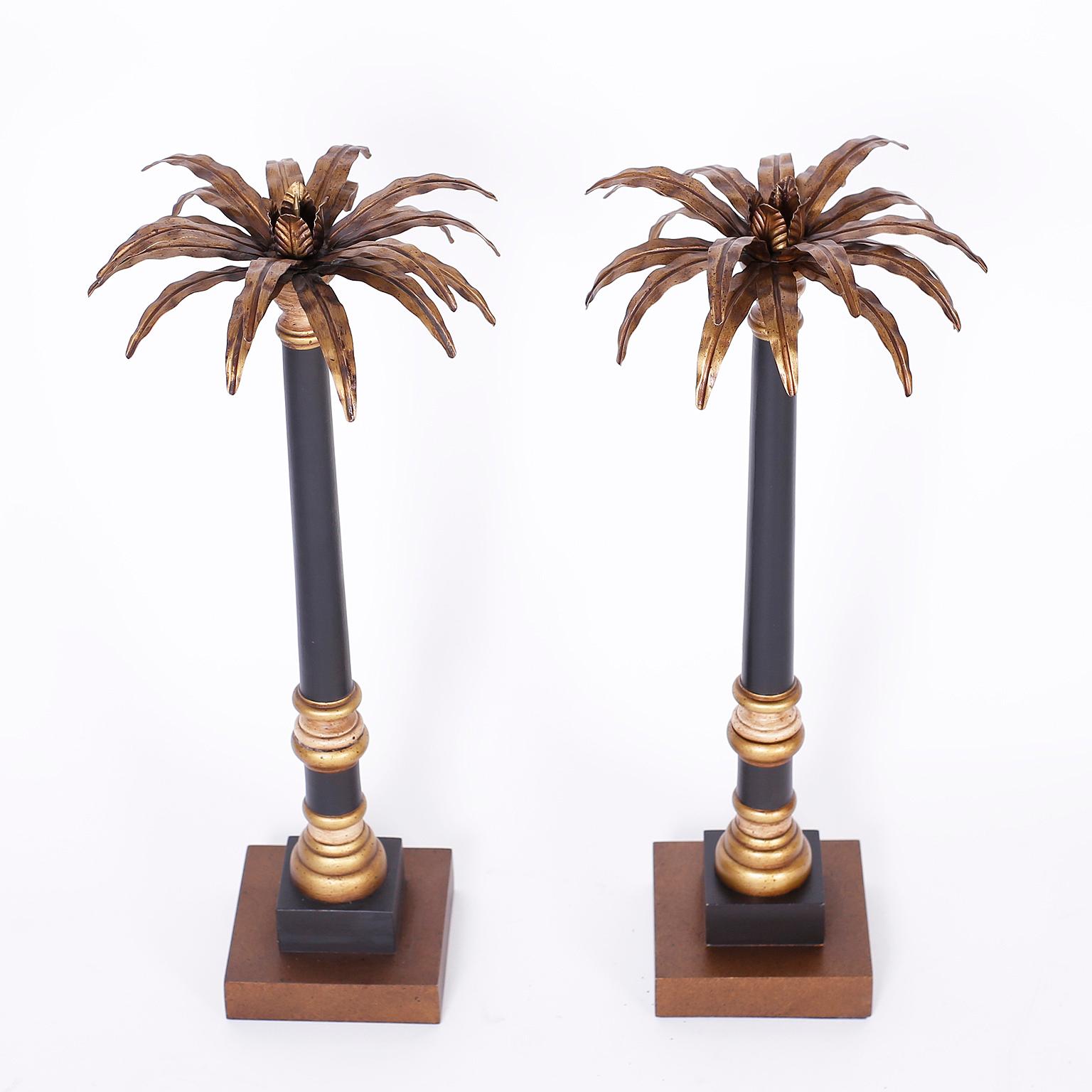 Pair of neoclassic Italian candlesticks with stylized brass palm tree tops having pricket candleholders over black and gold painted turned wood bases with classical form.
