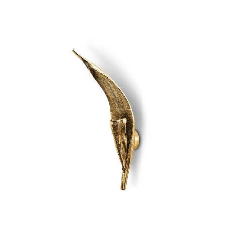La lampe murale Palm capture l'essence d'une écorce de palmier sèche, réimaginée en une œuvre d'art fonctionnelle saisissante. Fabriquée à la main en aluminium avec une finition polie, cette lampe exquise reflète la beauté organique de la nature
