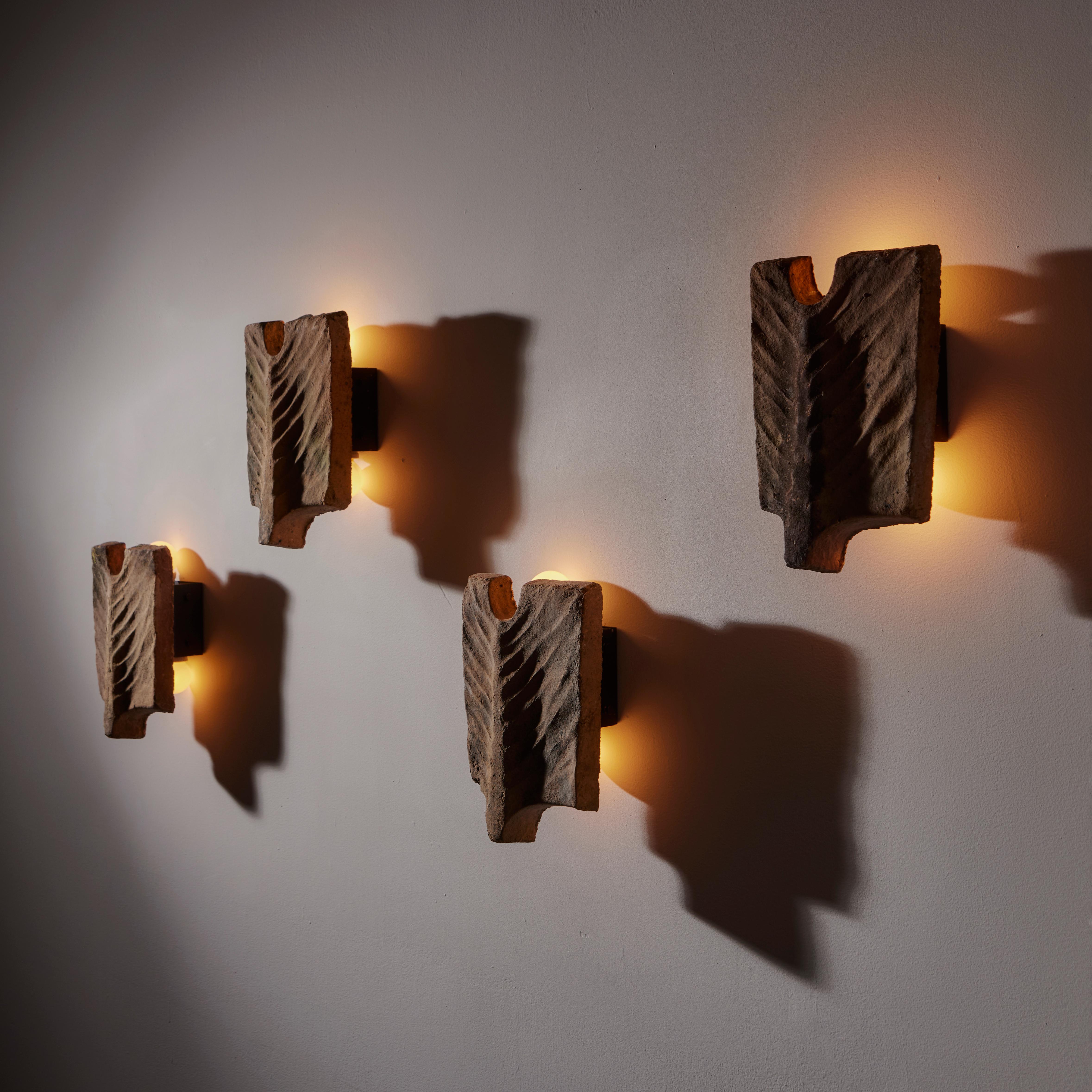 'Palme' sconces by Georges Jouve. Designed and manufactured in France, circa 1950s. Organic and anatomical sandstone forms make up these striking sconces. A steel structure behind the stone holds a double ended socket. Bulbs peak out of the top and