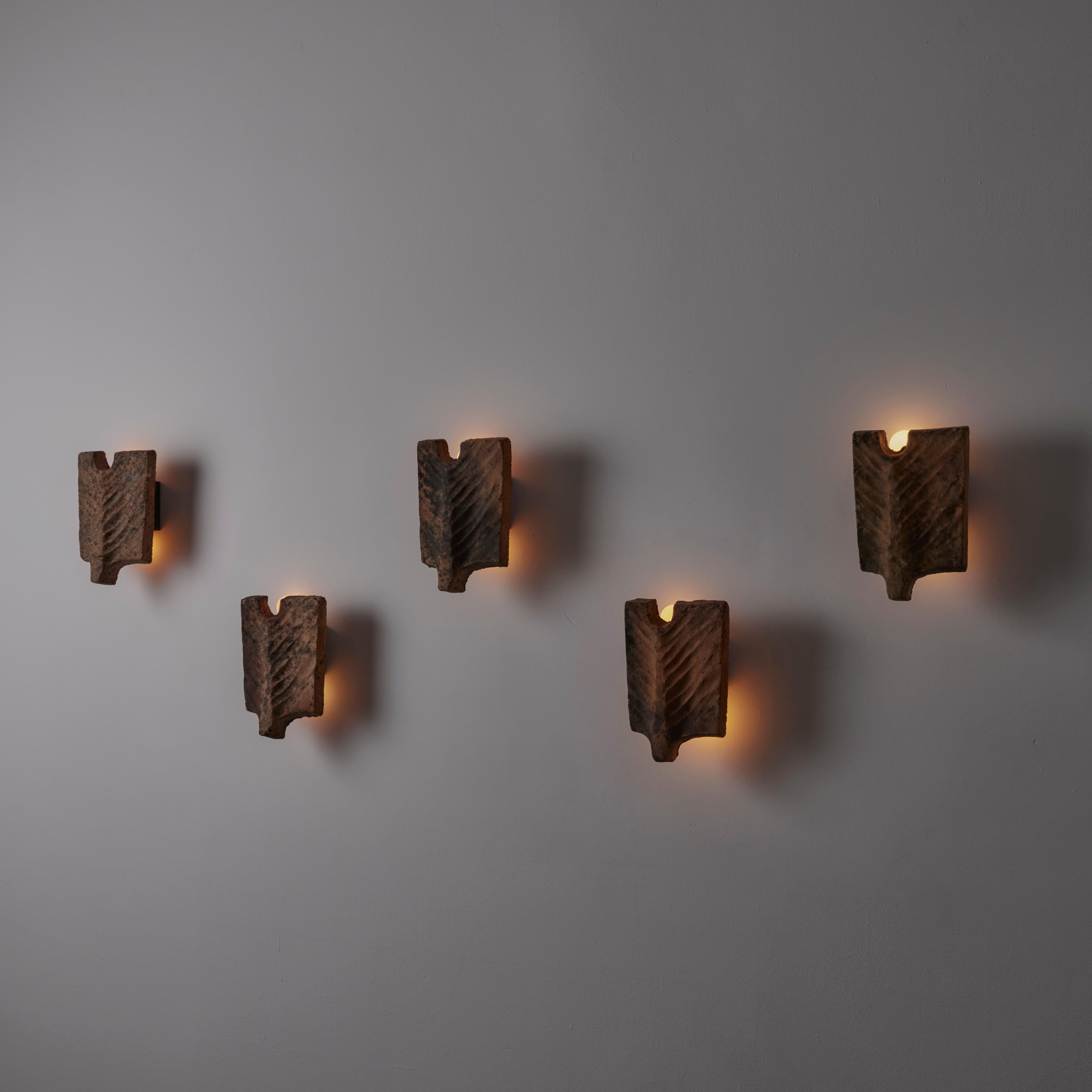 'Palme' sconces by Georges Jouve. Designed and manufactured in France, circa 1950s. Organic and anatomical sandstone forms make up these striking sconces. A steel structure behind the stone holds a double ended socket. Bulbs peak out of the top and
