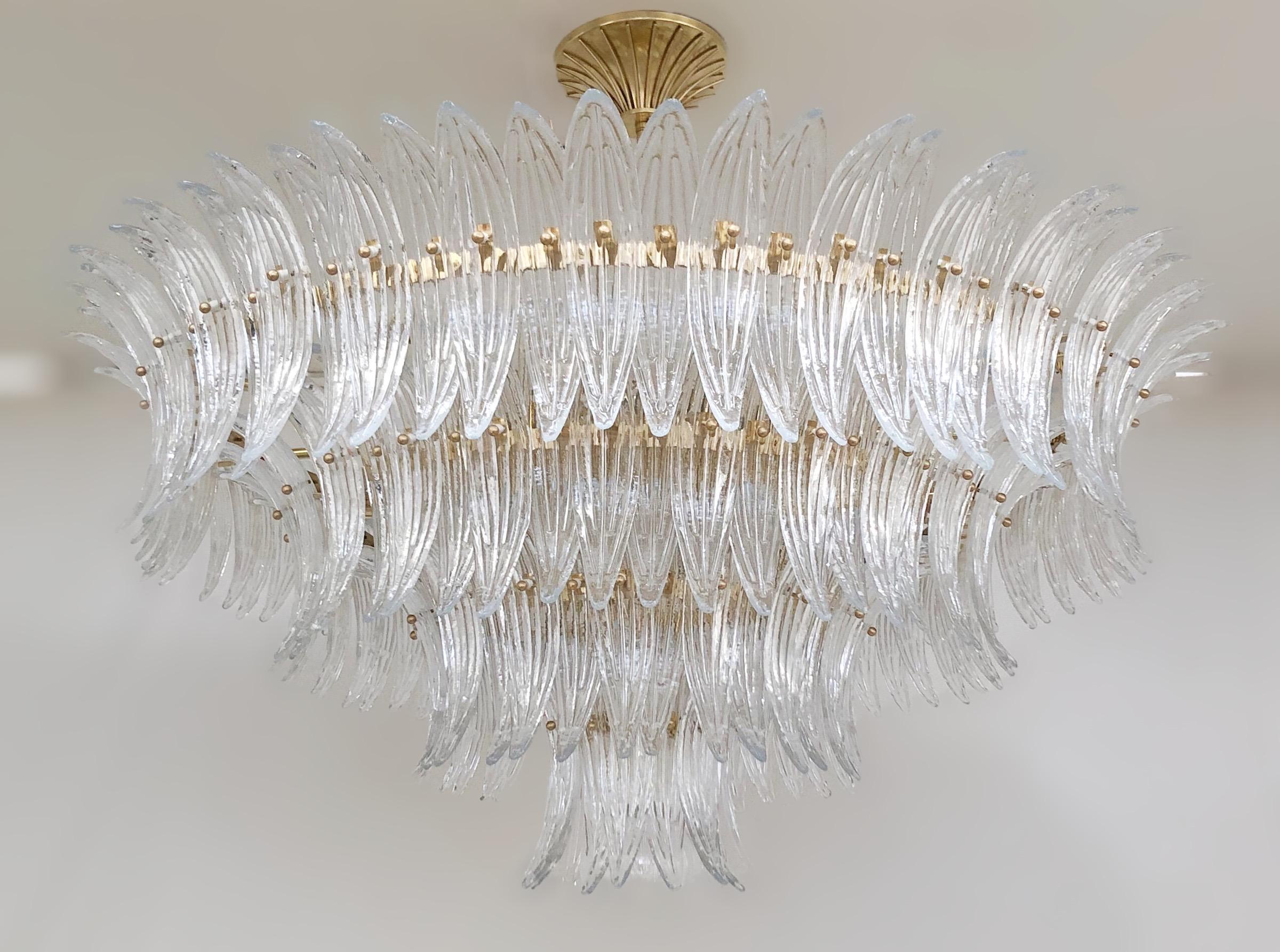 Italian Palmette chandelier shown in clear Murano glass leaves mounted on unlacquered natural brass finish frame with a clear glass ball / Made in Italy
Measures: diameter 47 inches, height 22 inches, total height 35.5 inches including rod and