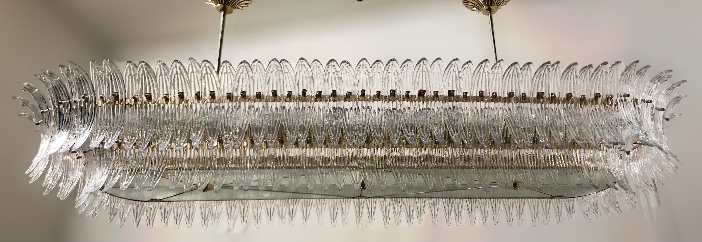 Italienischer Palmette-Kronleuchter mit Blättern aus klarem Muranoglas, montiert auf einem unlackierten Rahmen aus natürlichem Messing mit Diffusoren aus mattiertem Glas / Made in Italy
Länge 86,5 Zoll, Breite 31,5 Zoll, Höhe 13 Zoll, Gesamthöhe