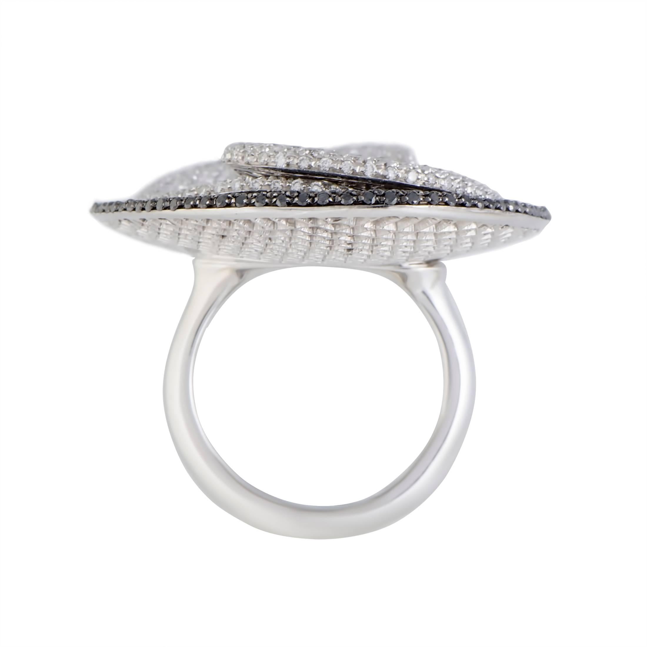 With a design reminiscent of a graceful flower, this gorgeous Palmiero ring enchants with its harmonious diamond setting. The ring is made of elegant 18K white gold and paved with white and black diamonds that weigh in total 10.63 carats.
Ring Size: