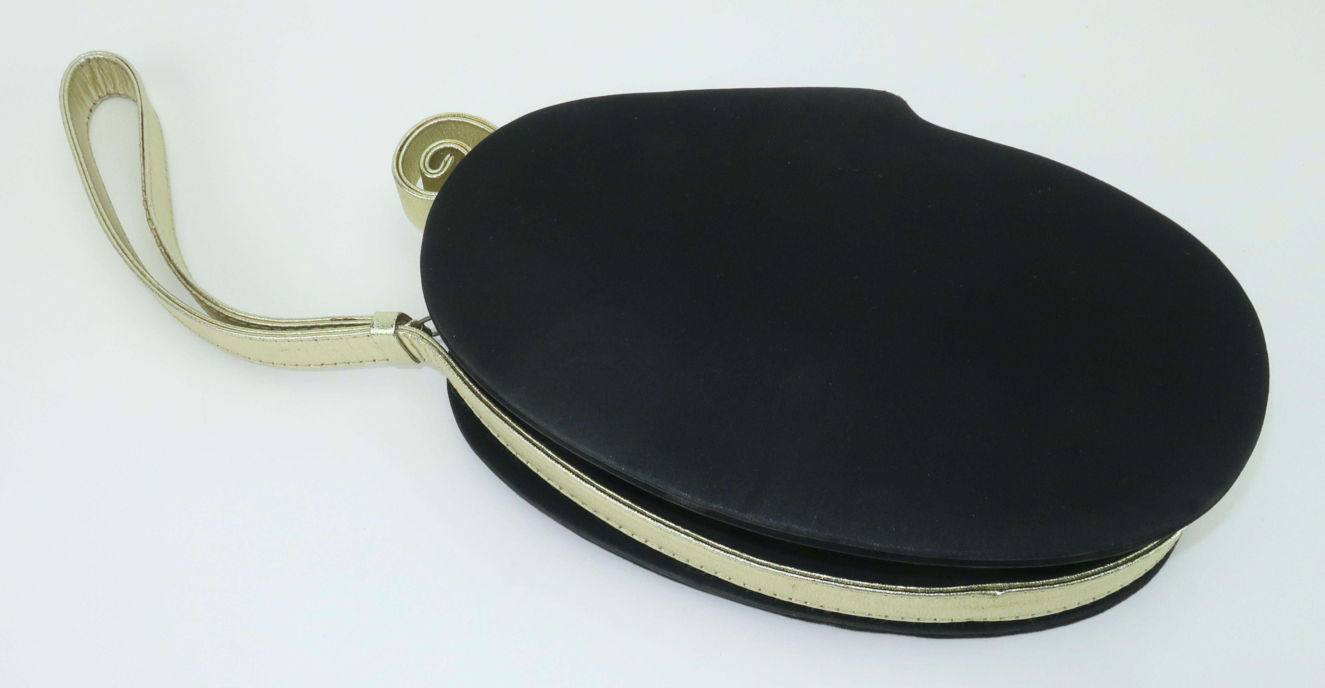 Bolso Paloma Picasso de los años 80 fabricado en Italia con una silueta única de estilo Art Déco. El bolso de satén negro de forma ovalada se acentúa con un asa dorada y un adorno en forma de rizo. El cierre de cremallera está unido al asa dorada y