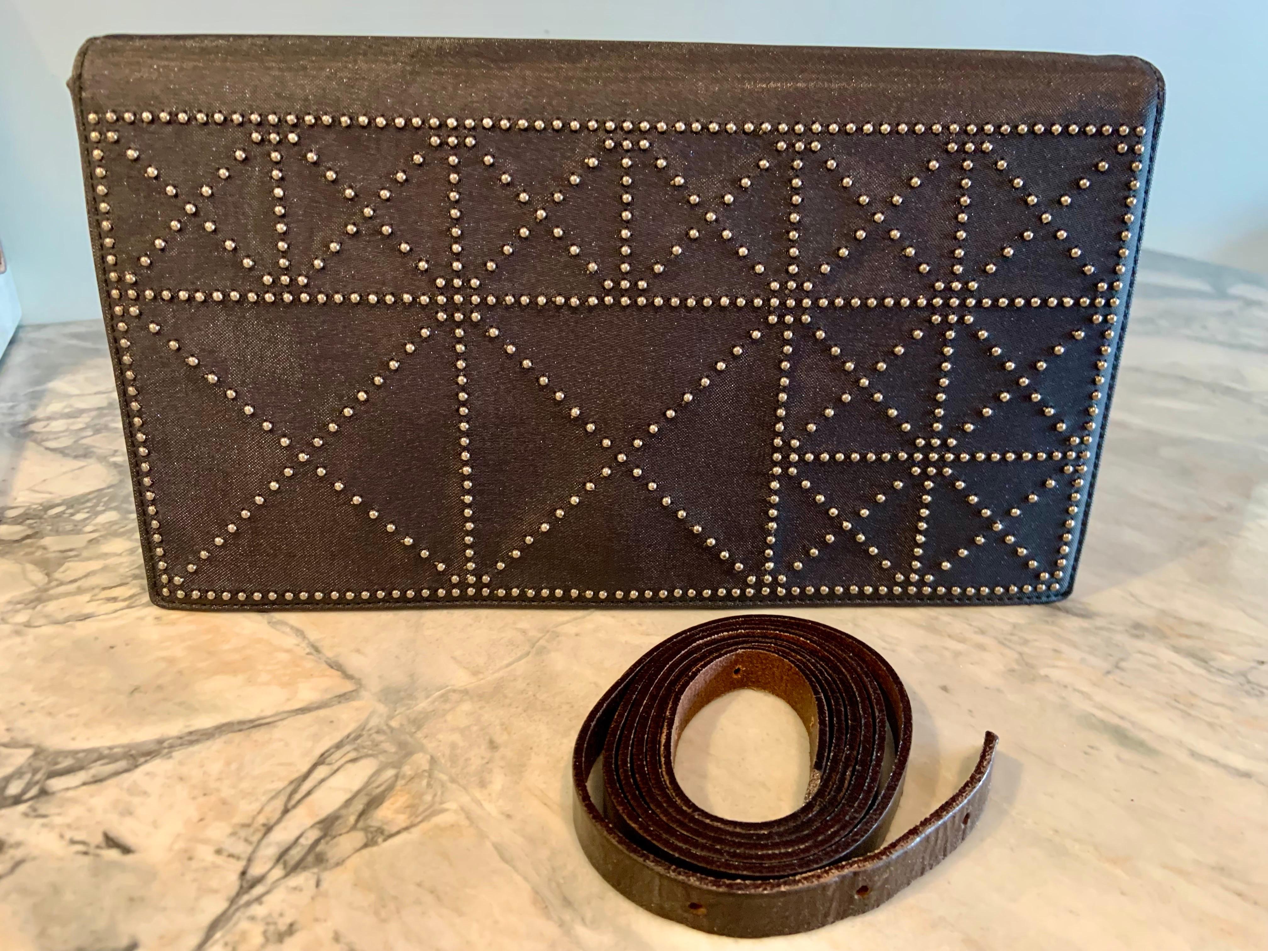Paloma Picasso ha disegnato questa elegante pochette o borsa crossbody con borchie di metallo sul davanti in due diverse dimensioni, creando una serie di X designs. L'interno della borsa è foderato in tessuto nero. C'è uno scomparto con cerniera sul