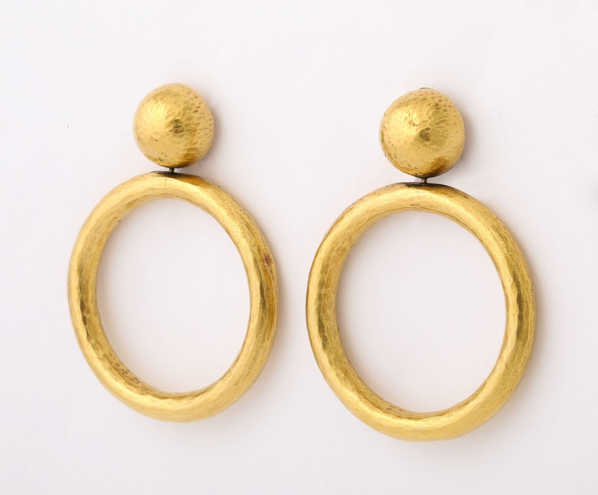 An iconic pair of vintage earrings by Paloma Picasso for Tiffany & Co., crafted in 18 karat yellow gold.
Each earring features a substantial open hoop suspended from a spherical stud. Both the hoop and stud have a subtle, hand-hammered texture,
