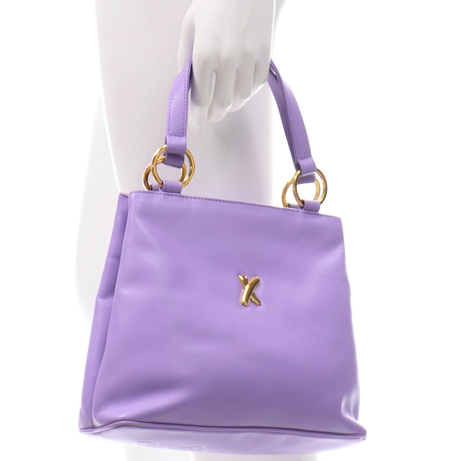 This is a perfect Spring and Summer vintage Paloma Picasso leather handbag! The bag is in a rare lavender purple and front of the handbag has the signature Paloma Picasso branded X hardware in a yellow gold tone. The bottom of the handbag has 