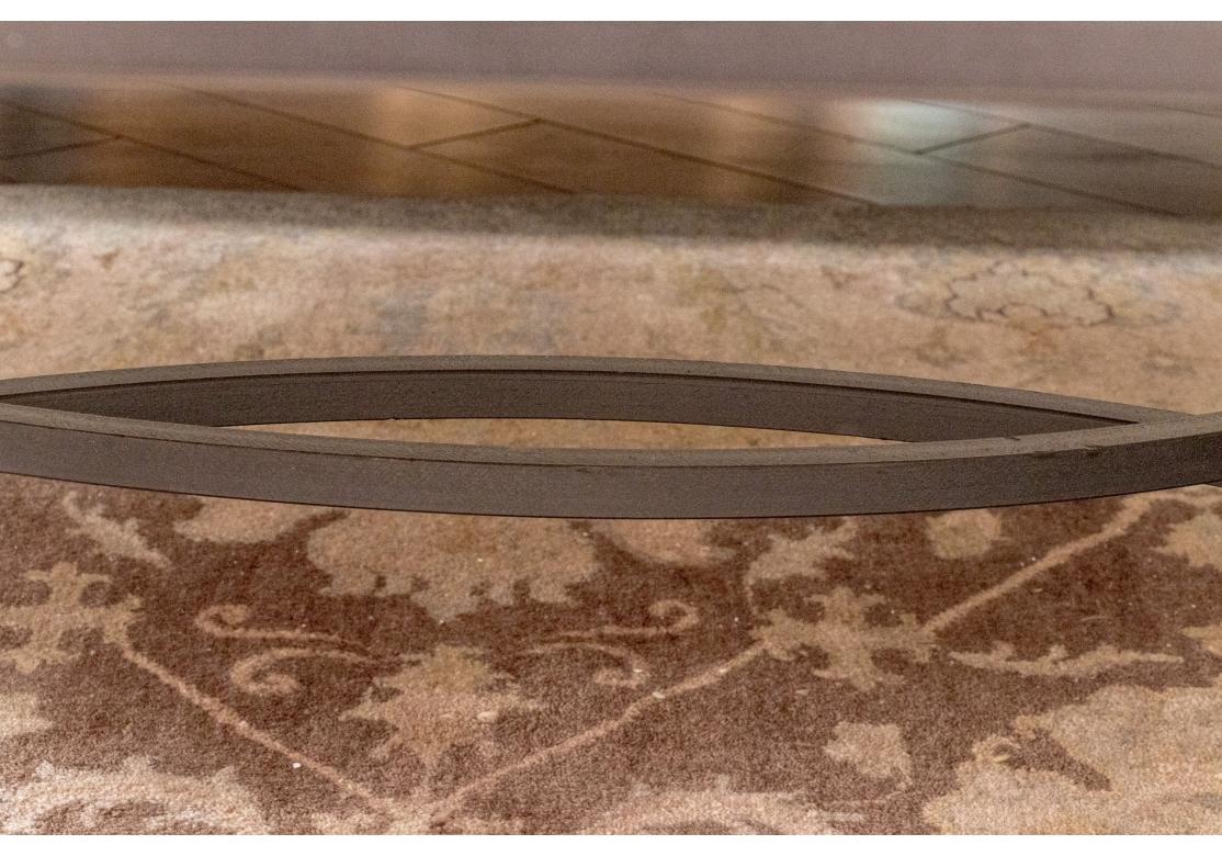 Table basse Kreiss Palomino composée d'une base en fer au fini bronze surmontée d'un plateau en pierre de travertin joliment biseauté. La base est munie d'un châssis en forme de navette et l'ensemble repose sur des pieds en forme de sphère et de