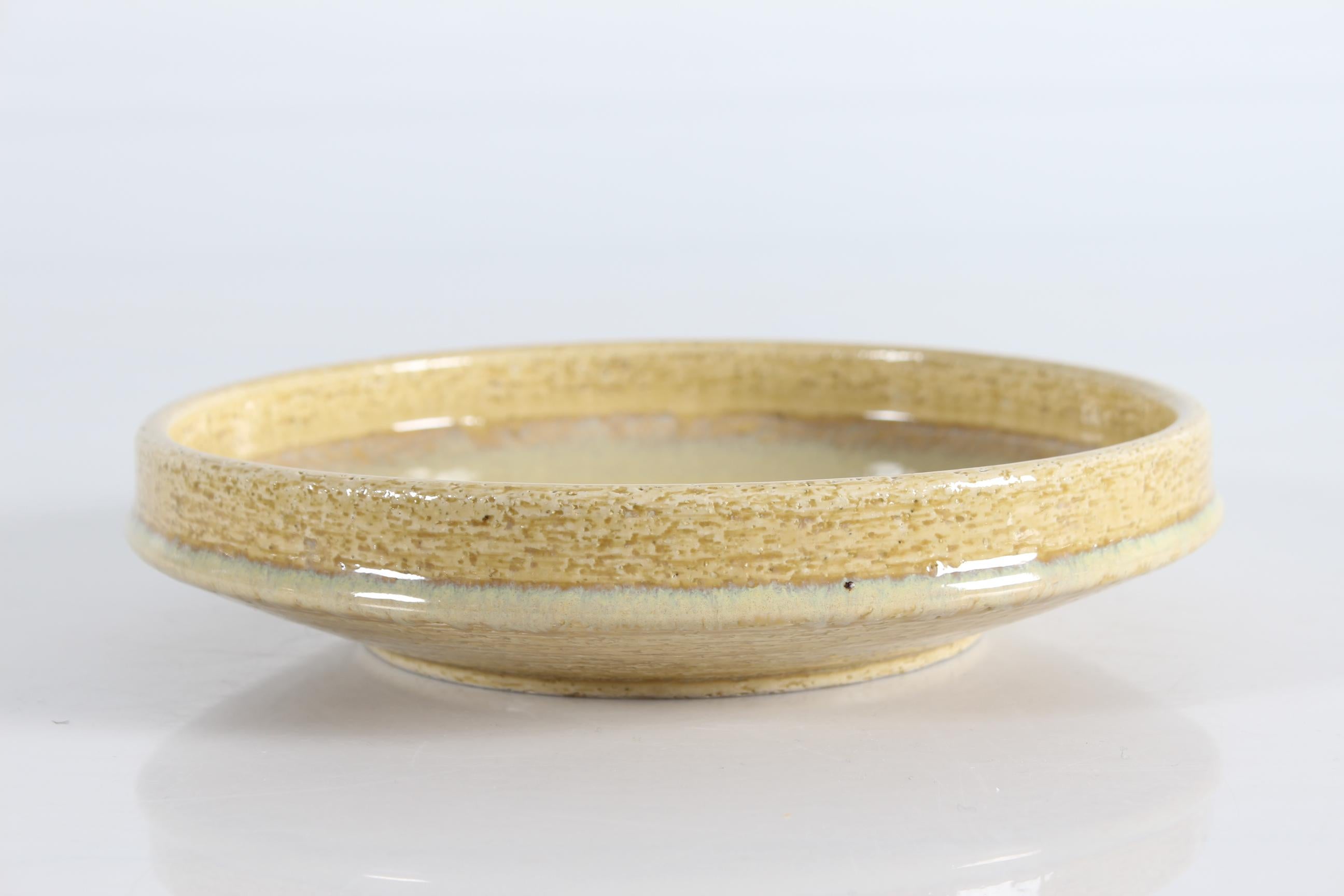 Flat stoneware bowl model no. C 103 by Per Linnemann-Schmidt for Palshus Denmark. Made ca 1960s.
It is made with chamotte clay which gives a rough and vivid surface. The glossy glaze is light yellow.

The bowl is fully marked on bottom with