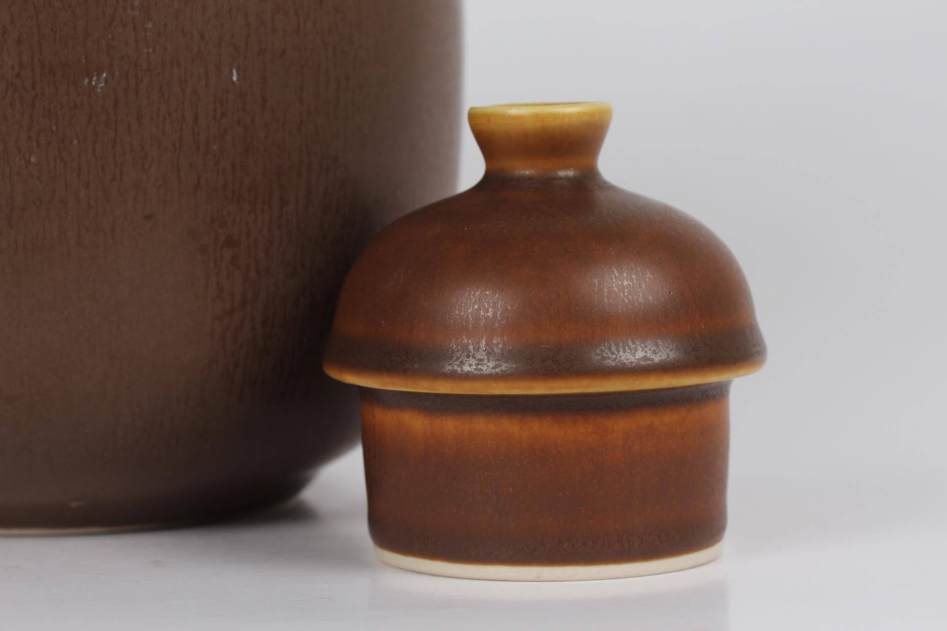 Ceramic teapot designed by the Danish ceramist Frode Bahnsen and manufactured by Palshus

The teapot is decorated with haresfure glaze in brown and ocher colors and has a bast handle 
Stamped in the bottom Palshus Denmark and FB for Frode