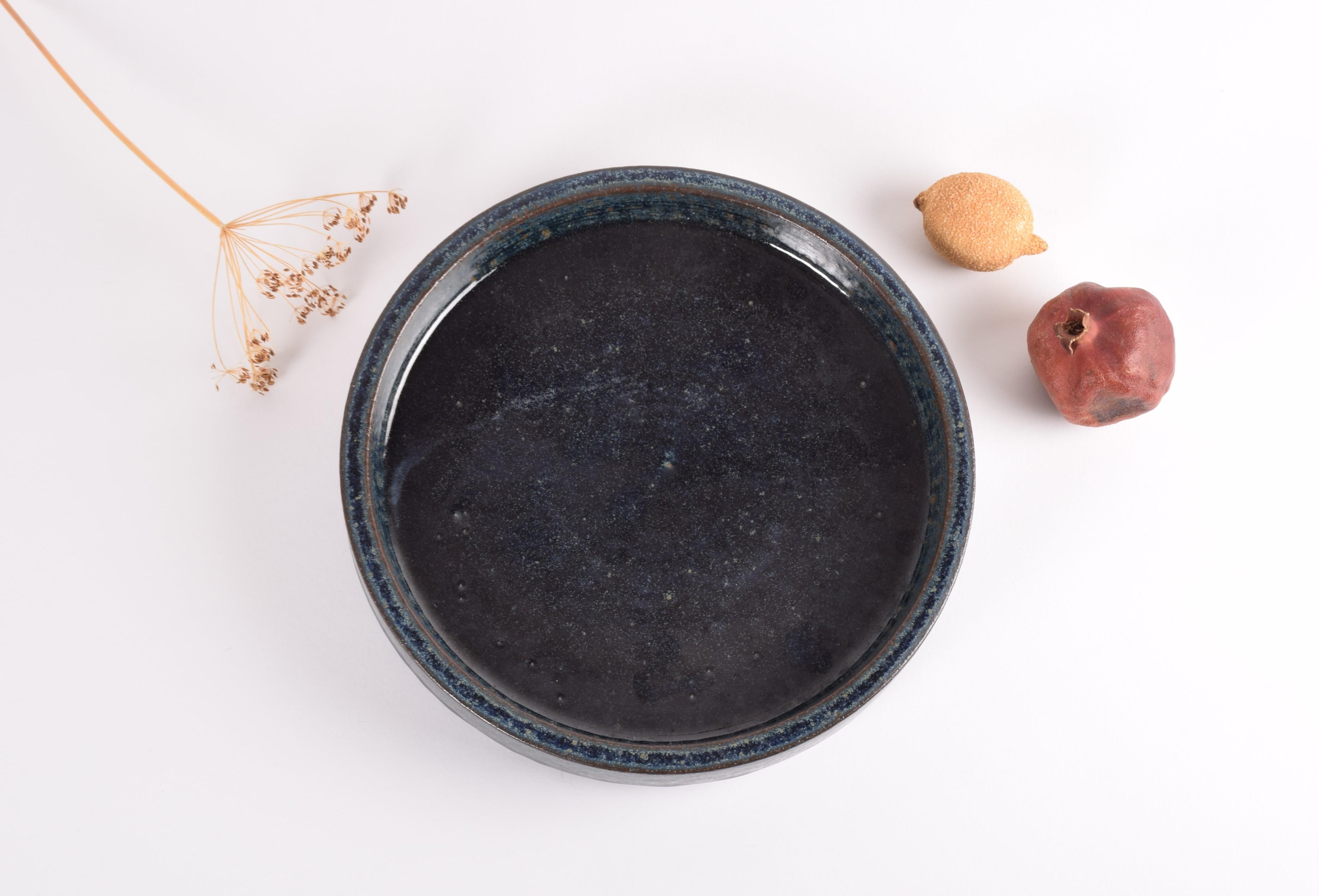 A large ceramic charger by Per Linnemann-Schmidt for Palshus Denmark. Made in the 1960s.
It is made with chamotte clay and has an interesting dark blue glaze with brown, beige and pale green speckles. 

The charger is fully marked on bottom.