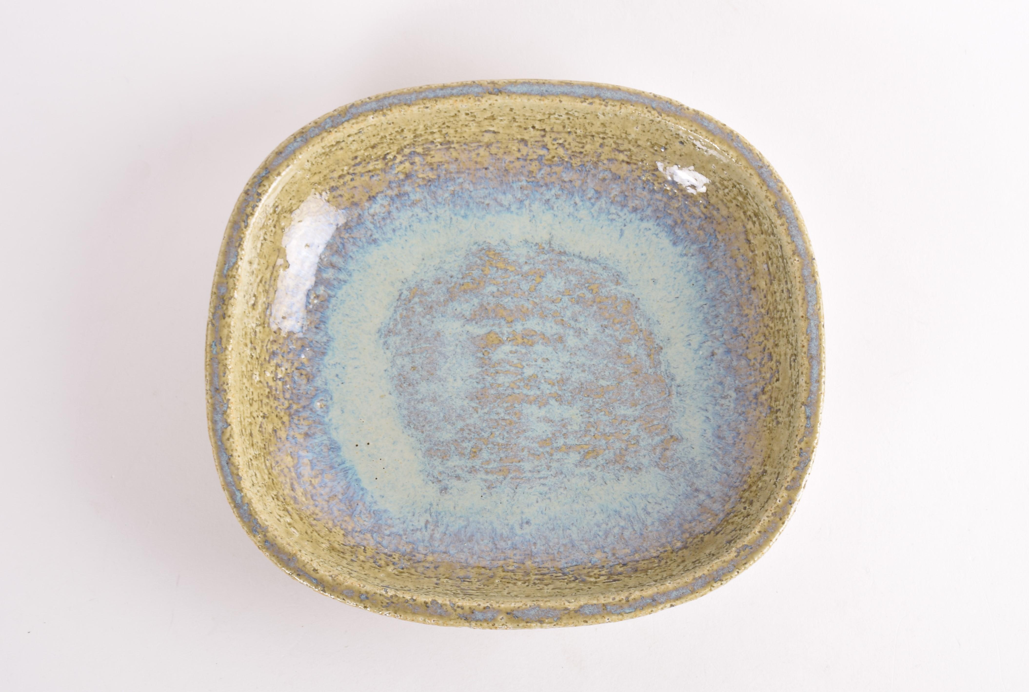 A large ceramic flat bowl by Per Linnemann-Schmidt for Palshus Denmark. Made ca 1960s.
It is made with chamotte clay which gives a rough and vivid surface. The glaze is a beautiful play between a dusted green and pale blue. 

The bowl is fully