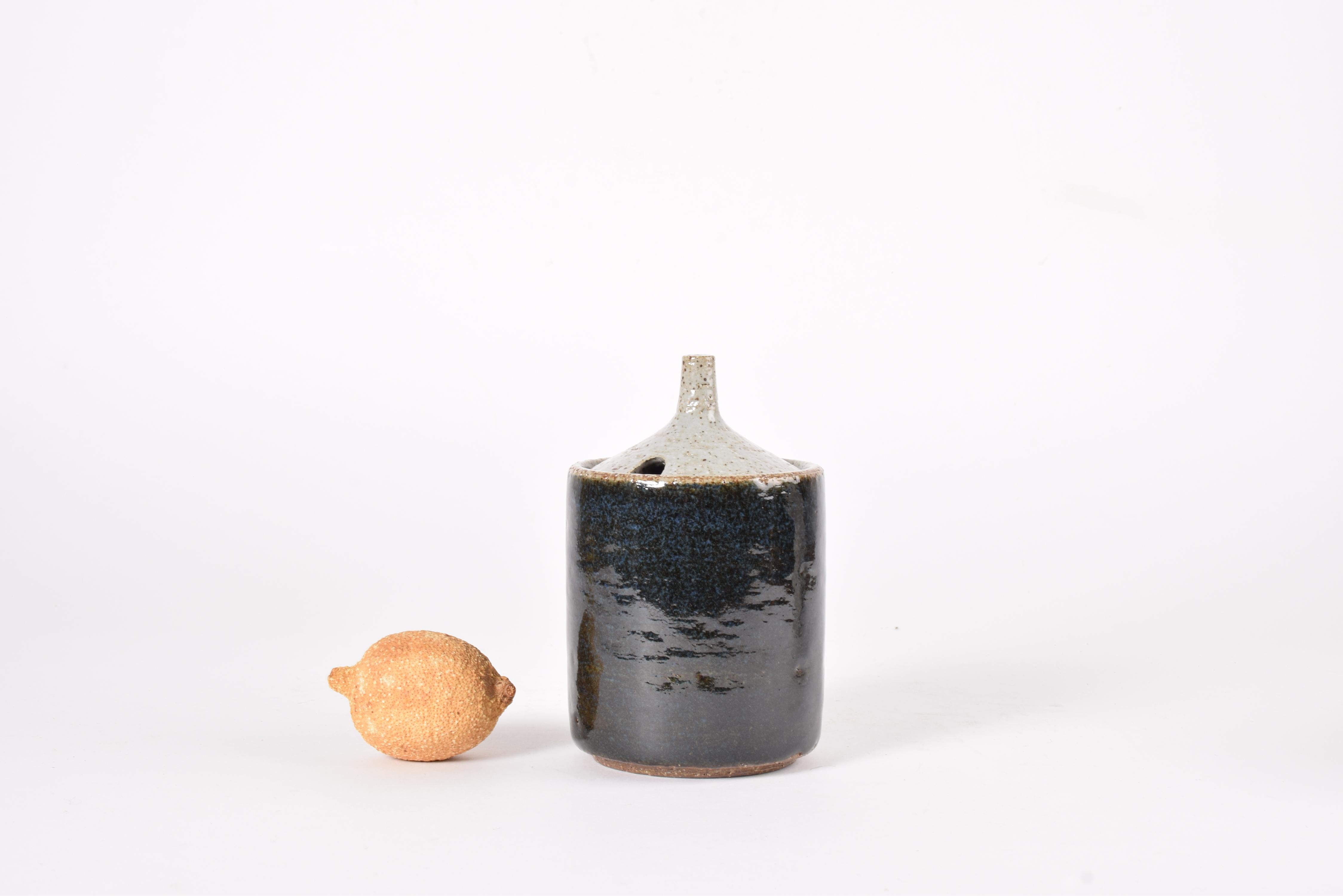 Jarra con tapa rara de encontrar, obra de Per Linnemann-Schmidt para el estudio de cerámica Palshus Dinamarca. Fabricado hacia la década de 1960.

Está hecha de gres y presenta un vidriado azul oscuro con elementos marrones en el cuerpo y un