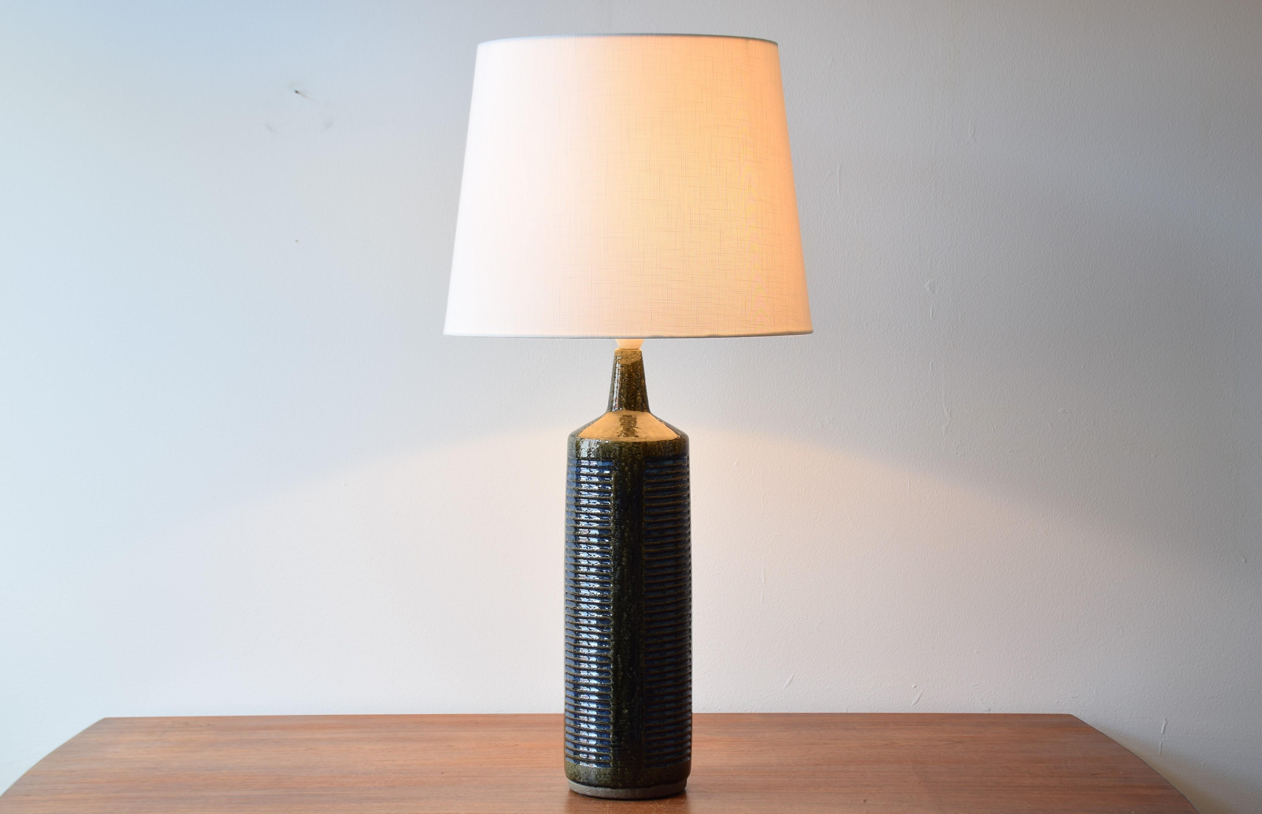 Very tall vintage Palshus Denmark table lamp including new quality lampshade!

The lamp was designed by Per Linnemann-Schmidt and produced circa 1960s. The glaze is bottle green with cobalt blue and the lamp is made with chamotte clay which gives