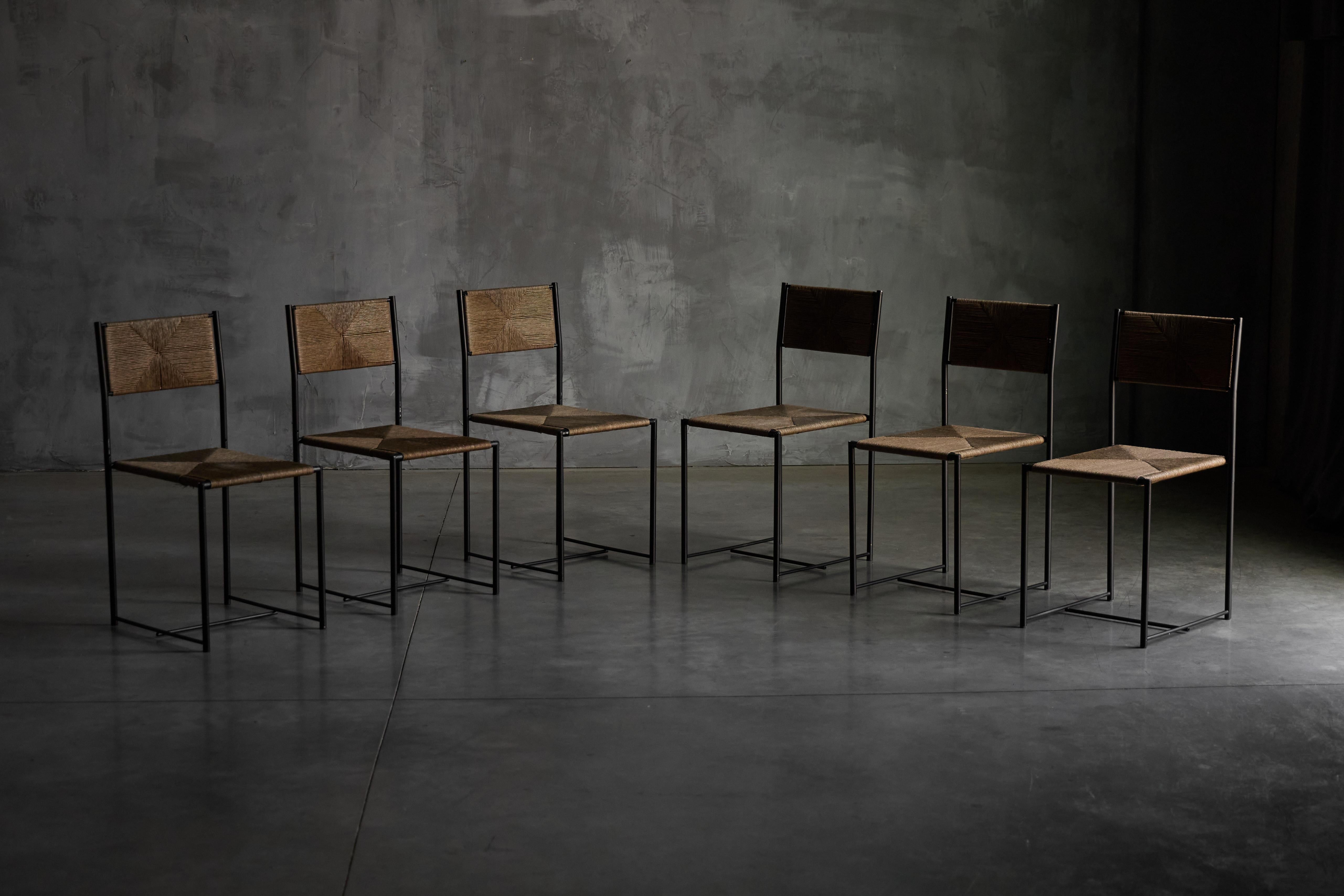 Paludis 150 chairs, designed in 1979 by Giandomenico Belotti for Alias, a refined example of Italian minimalist design. Each chair features a slim, black steel frame with clean lines, complemented by a hand-woven seat and backrest made from natural