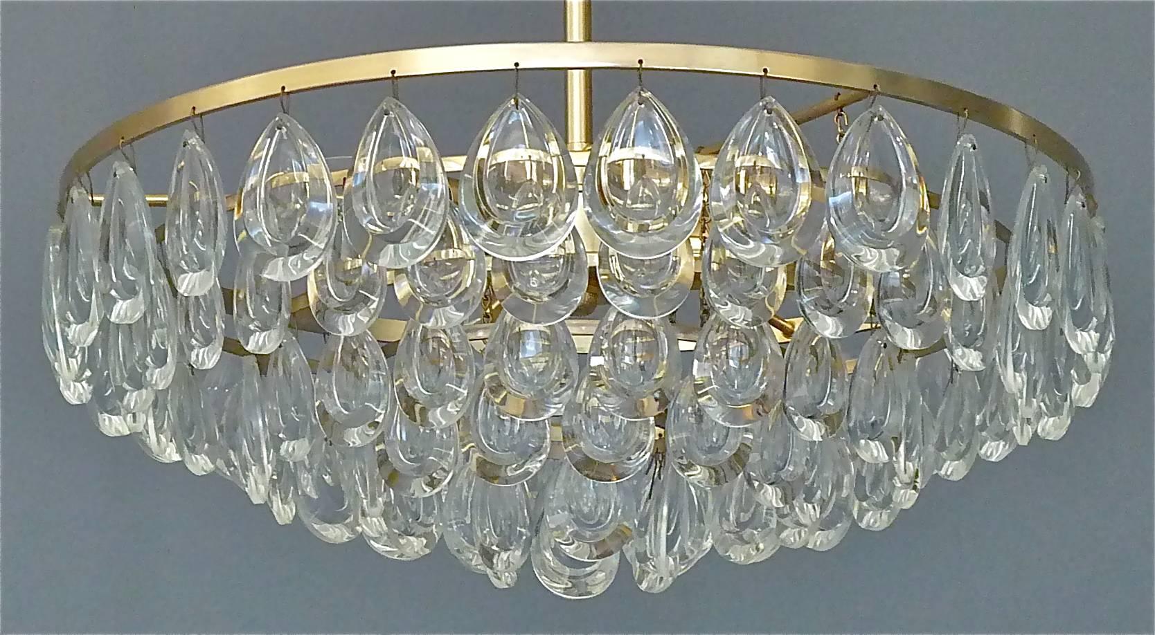 A beautiful five tiers crystal glass optical teardrop chandelier made by Palwa, Germany, circa 1960. The chandelier has a hand-cut faceted crystal glass sphere or globe in the center of the stem and five faint gilt brass metal rings with lots of