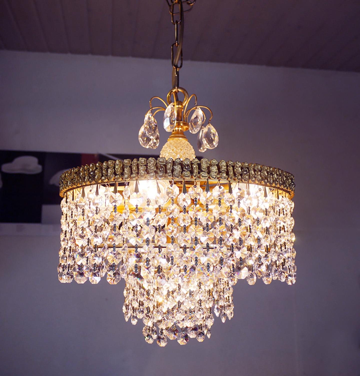 Elegant lustre à bulles en cascade avec des cristaux montés sur une monture en laiton doré. Les cristaux suspendus rappellent les rayons du soleil réfractés des milliers de fois dans la lumière. Le lustre éclaire magnifiquement et offre beaucoup de