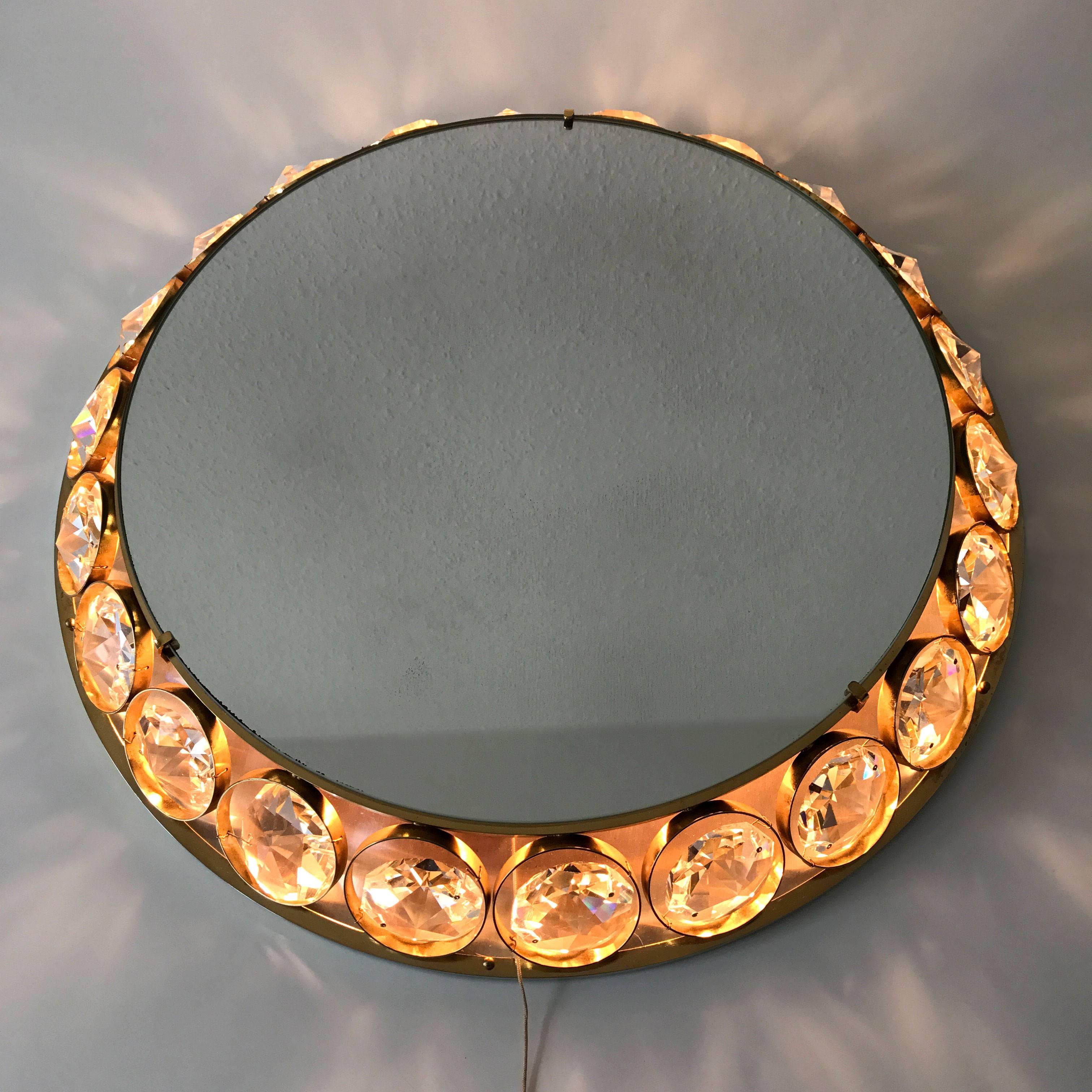 Highly decorative Mid Century Modern backlit wall mirror with a brass frame and large crystal elements. Designed and manufactured by Palwa, Germany, 1960s. 

Executed in crystal glass elements, gilt brass and mirrored glass, the wall mirror needs 6