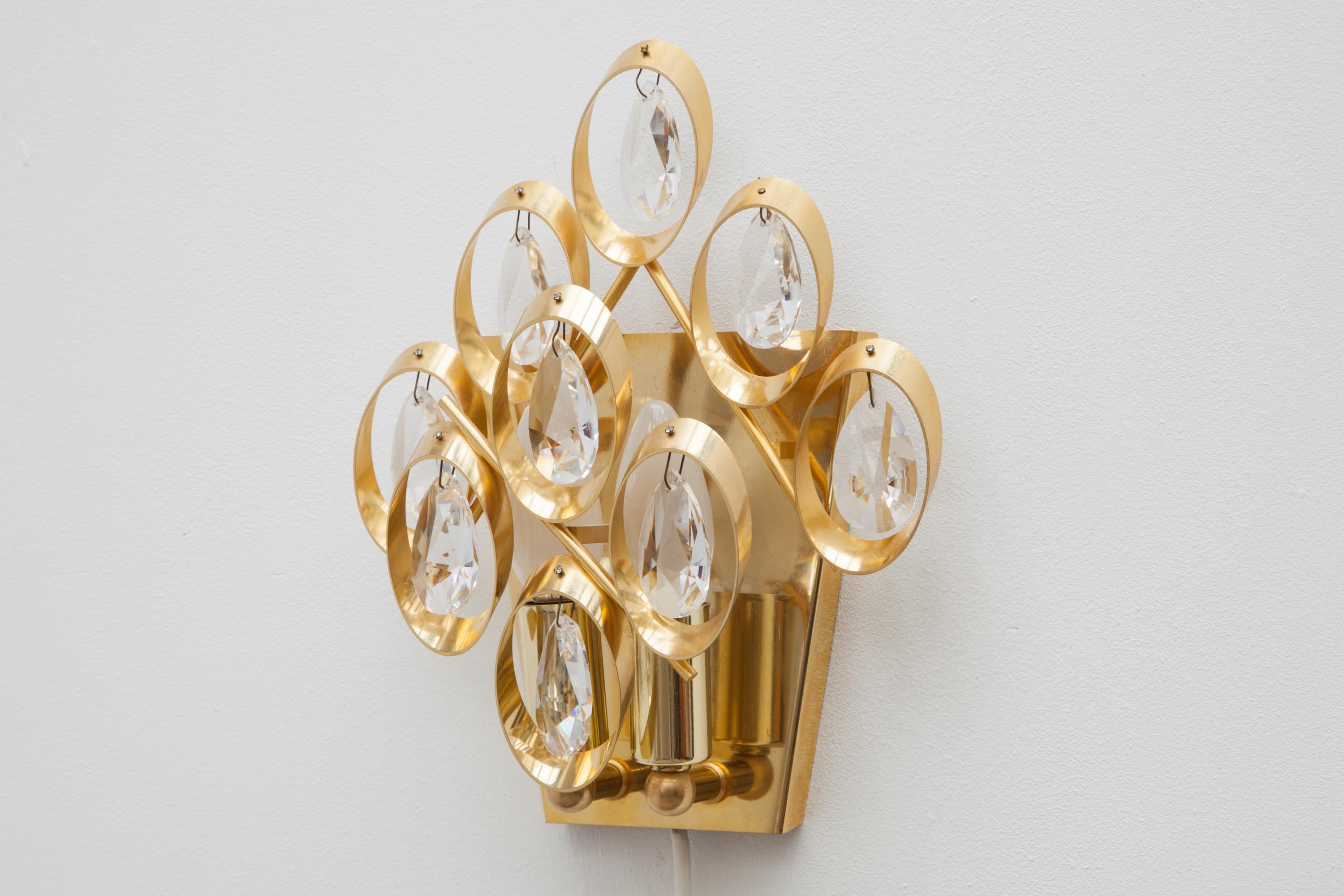 Set of two 1960s wall lights by Palme and Walter, Germany.
Features eight glass crystal teardrops on a frame made of brass, gilt circles.
Lit by two bulbs.23.5 W x 28 H x 10 D cm.