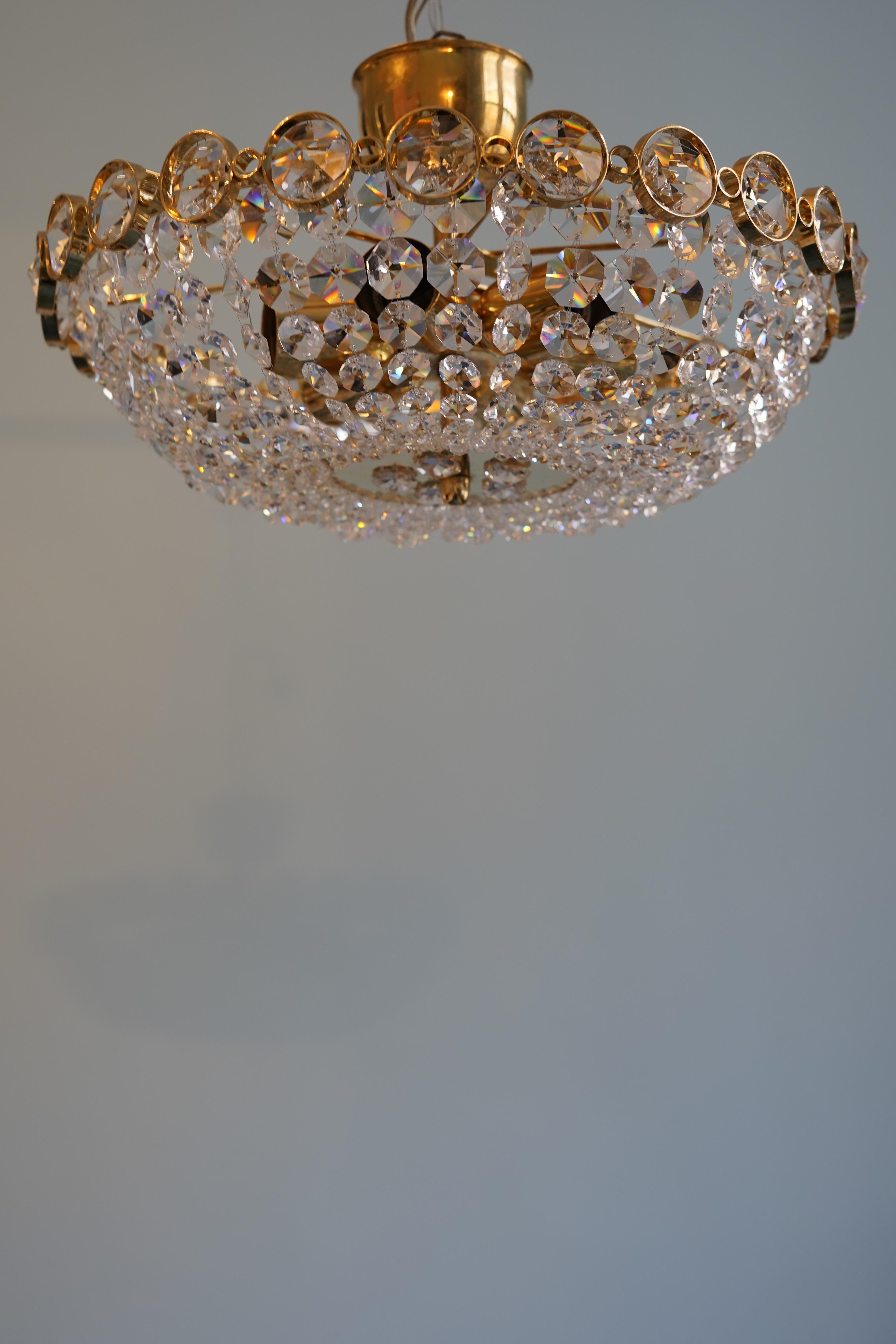 Chandelier ,chunky diamond cut crystal in various sizes on a gilt brass frame By Palwa, Austria, 1970.
Highly saturated frame with various sized crystals cut in an octagonal shape surrounding the bottom which is a high polished round flat brass