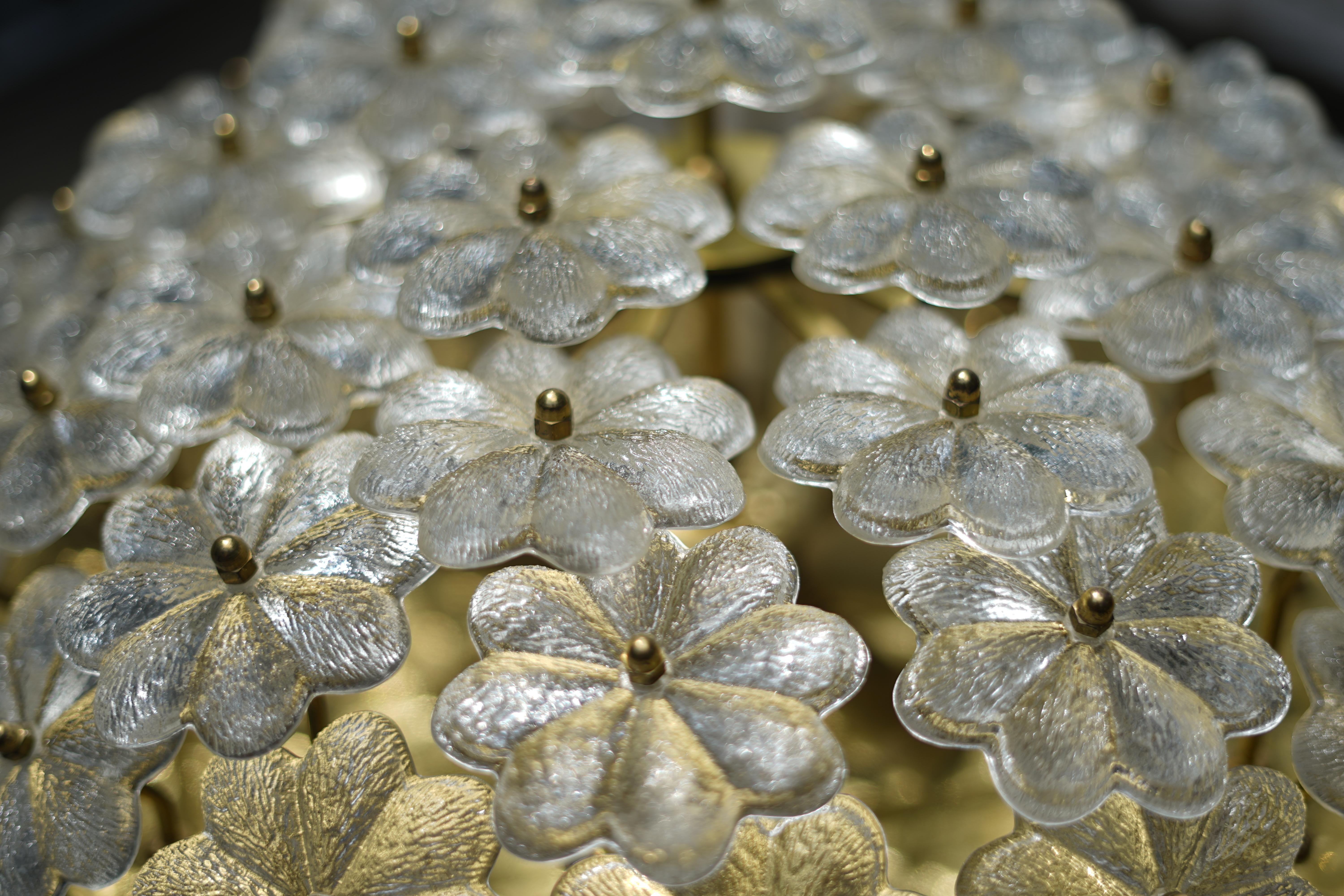 Polished brass base with 6 candelabra sockets, numerous individual large clear glass in the shape of a flower forms a shade.