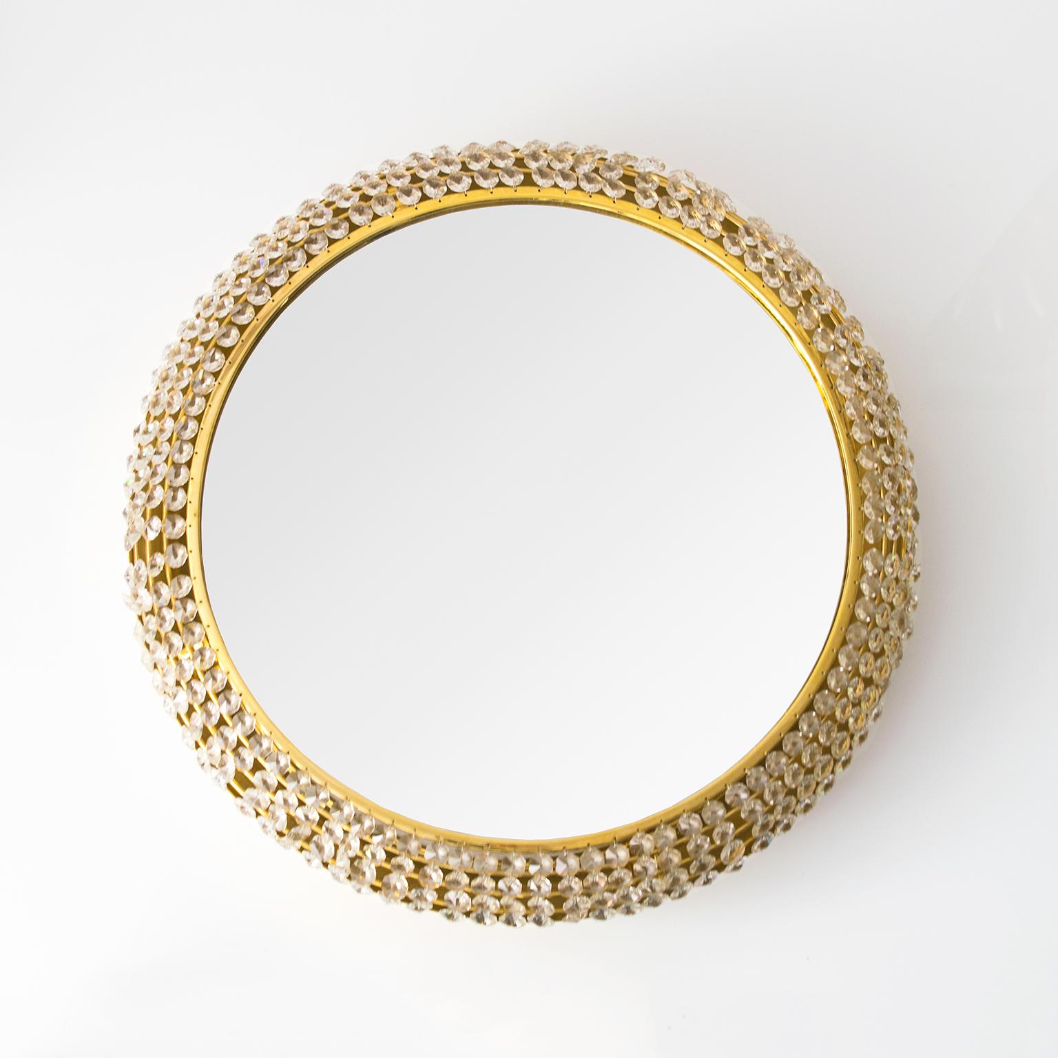 Un brillant miroir rond en laiton doré de style Midcentury Modern avec des douzaines de rangées de cristaux suspendus au-dessus d'une plaque arrière électrifiée contenant six douilles à base de candélabre. Nouvellement recâblé, le miroir est équipé
