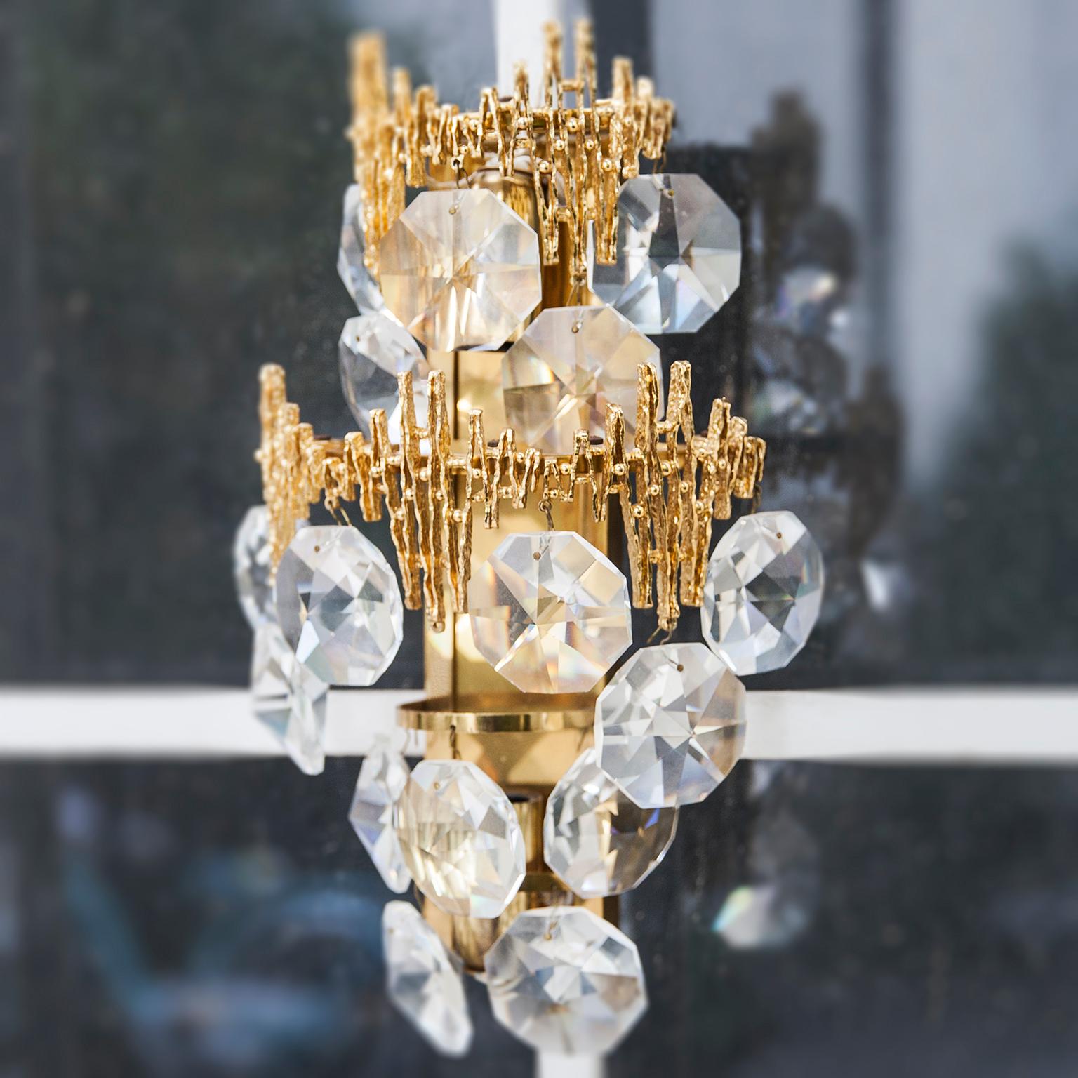 Hollywood Regency style wall light in gilt brass and with 16 glass crystals made by Palwa, Germany, 1960s. This Hollywood Regency crystal glass disc sconces, has a frame of real gilt metal. It needs two x E14 standard screw bulbs to illuminate. This